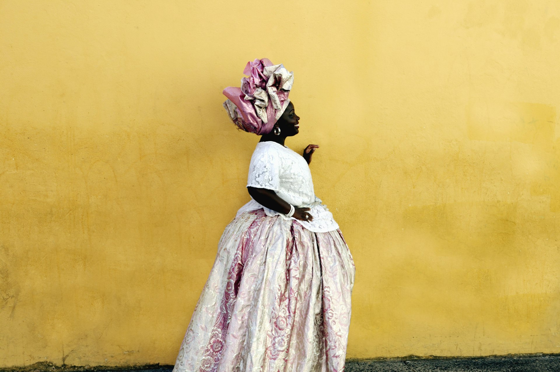 Features - Woman wearing traditional Brazilian clothing, standing by yellow wall