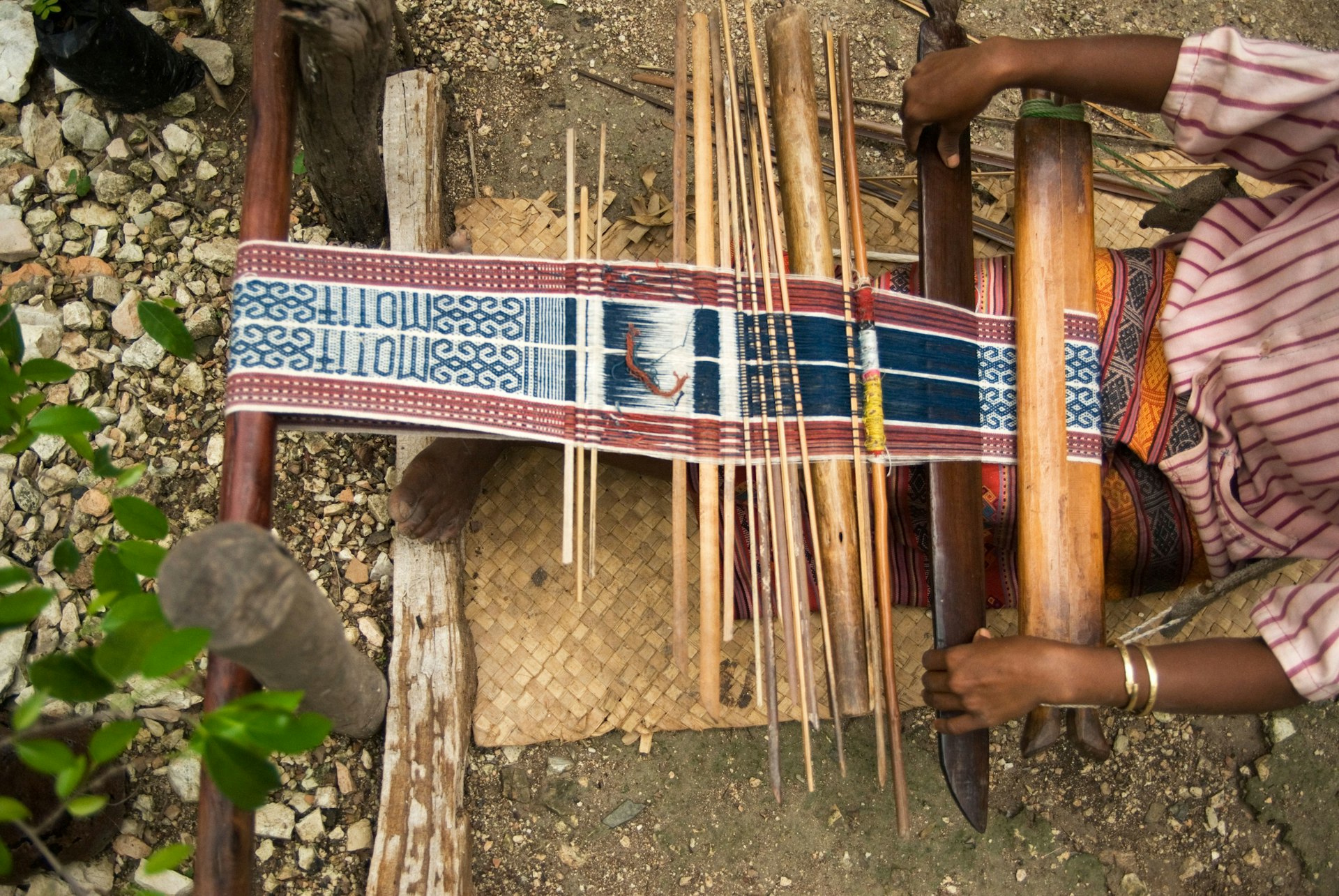 Features - Woman weaving ikat cloth on backstrap loom.