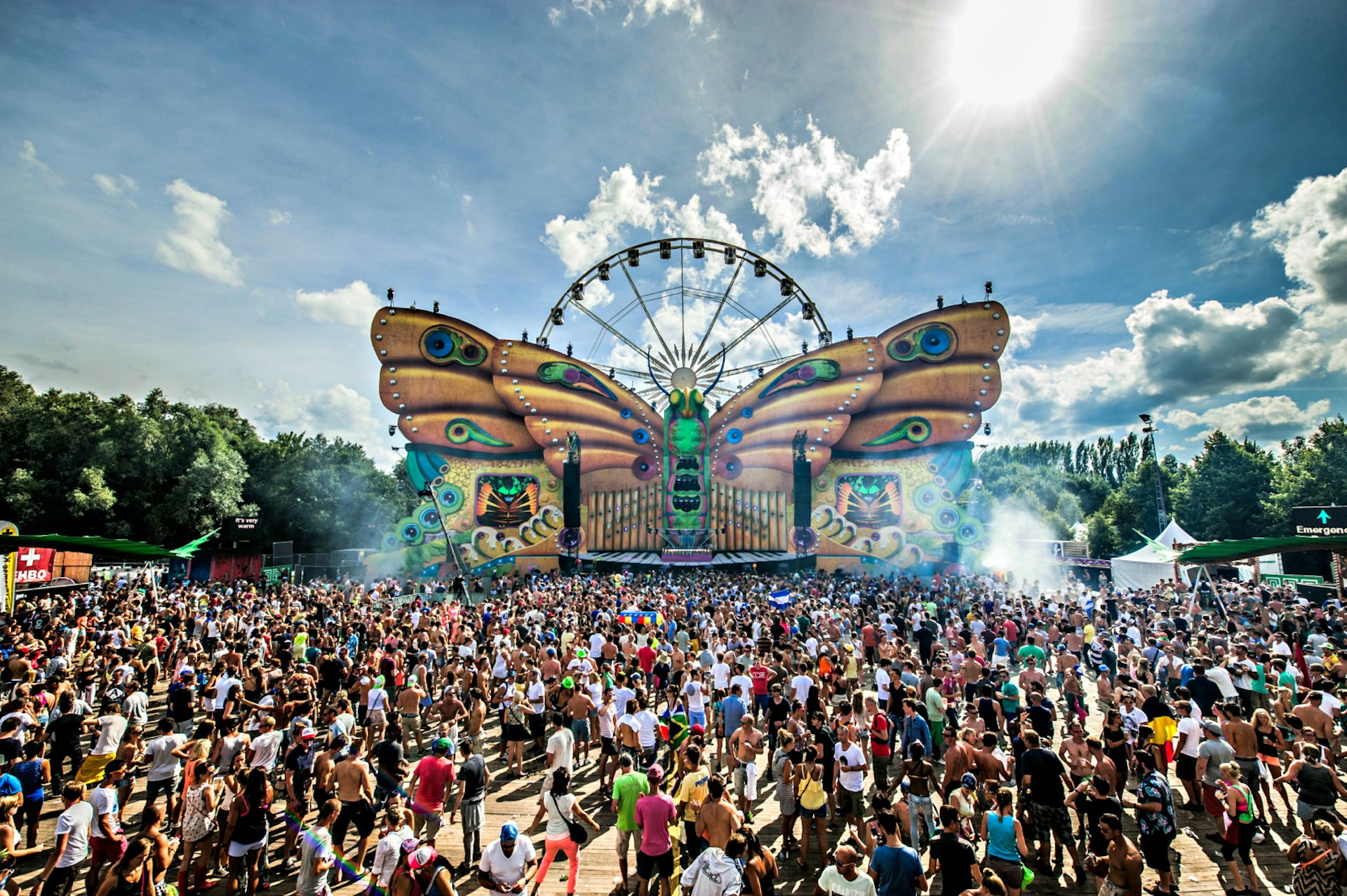 The crowd waits in front of a butterfly stage and a ferris wheel during the third day of the ninth edition of the Tomorrowland music festival