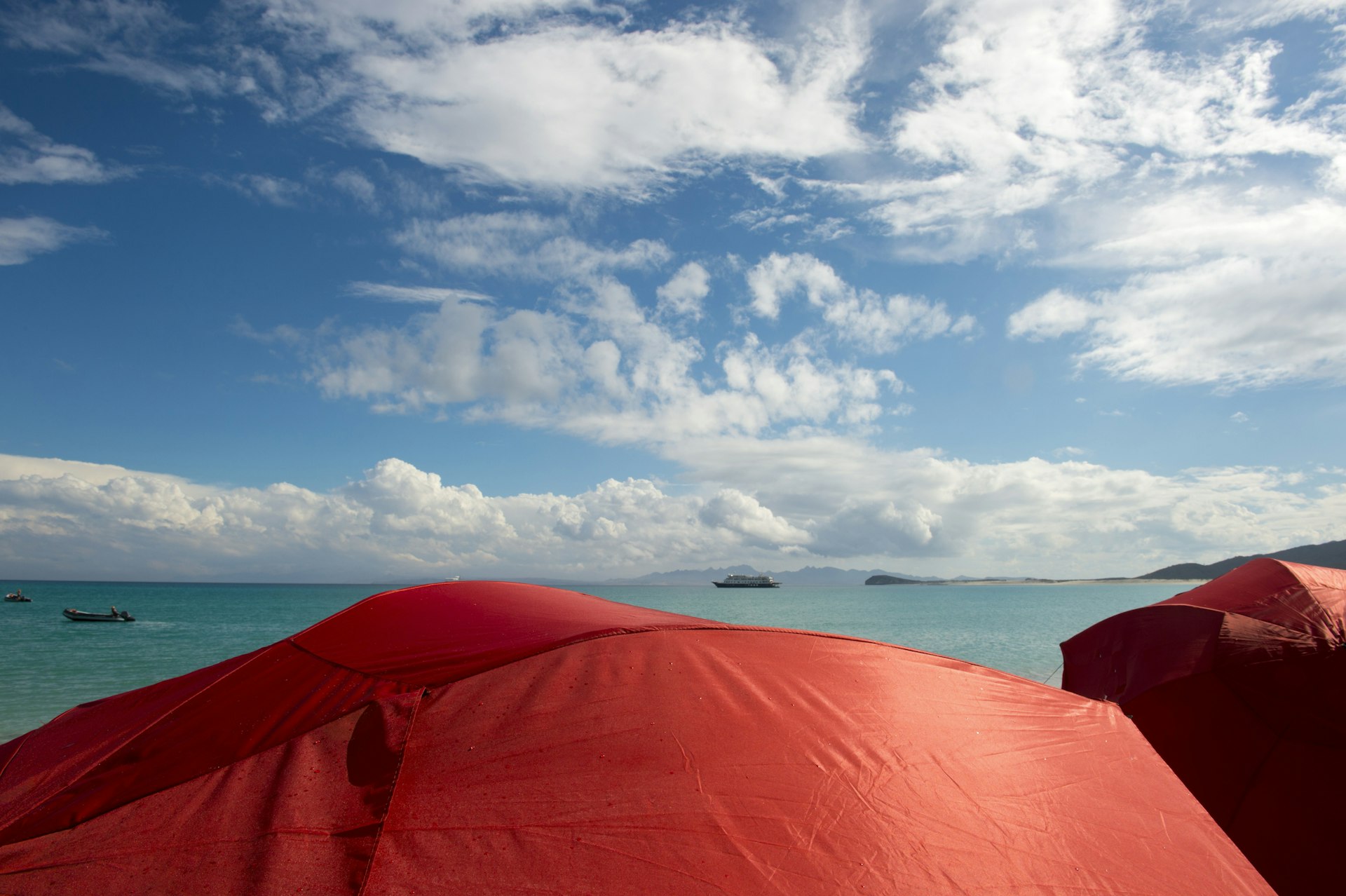 Red sun umbrellas on a beach on the Isla Espiritu Santo in the Bahia de La Paz, Sea of Cortez in Baja California Mexico