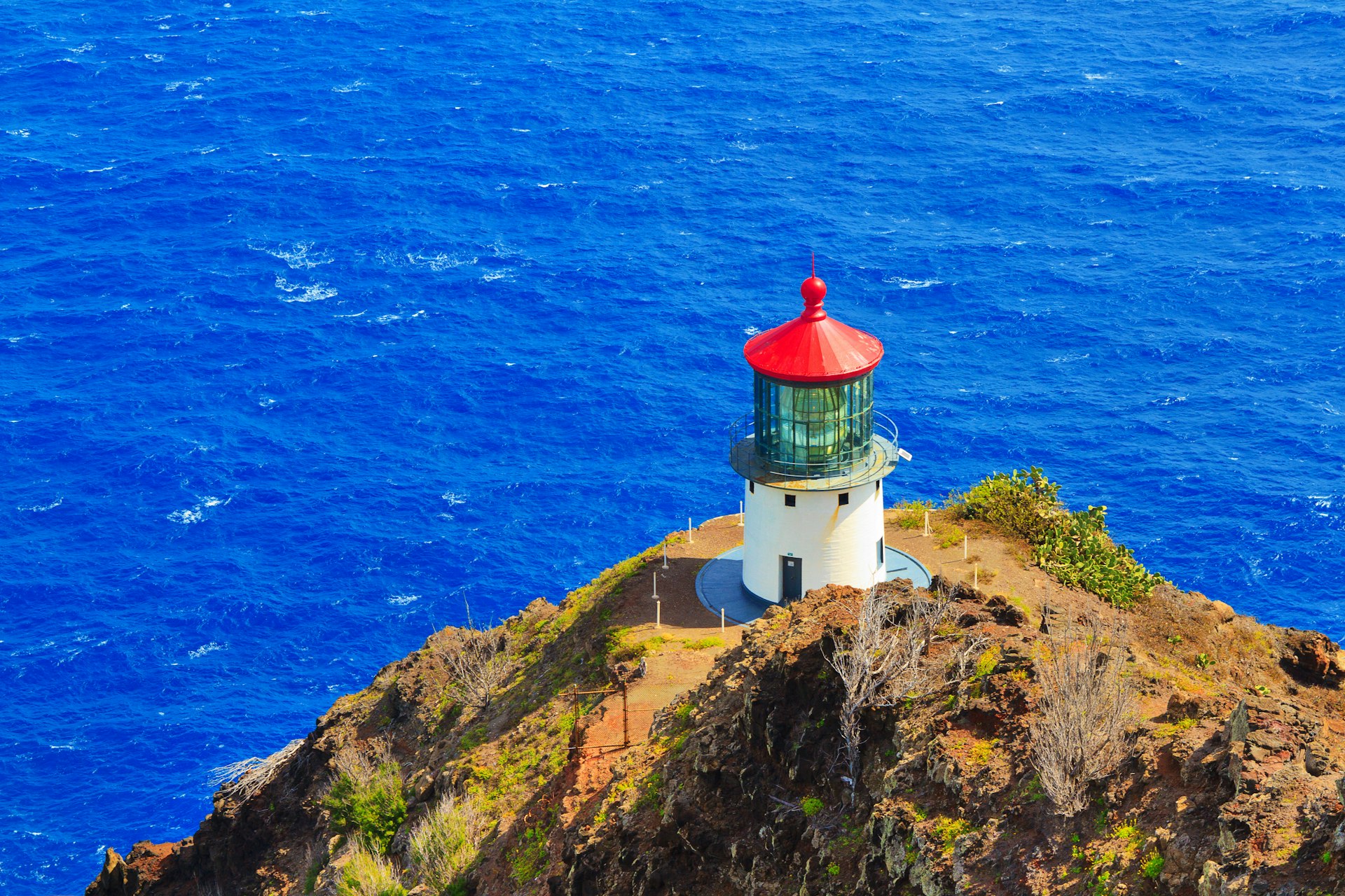 Makapu'u Point Lighthouse on edge of Pacific Ocean, viewed from above from Makapu'u Point summit overlook. The lighthouse is run by the US Coast Guard.