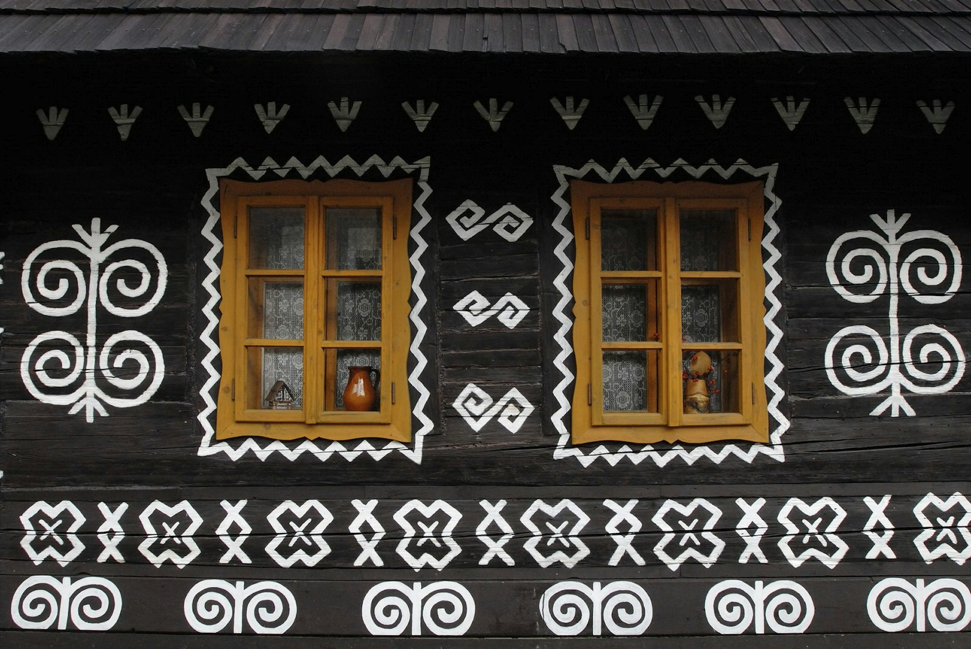 A black cottage painted with intricate white designs in Central Slovakia © Axiom Photographic / Getty Images