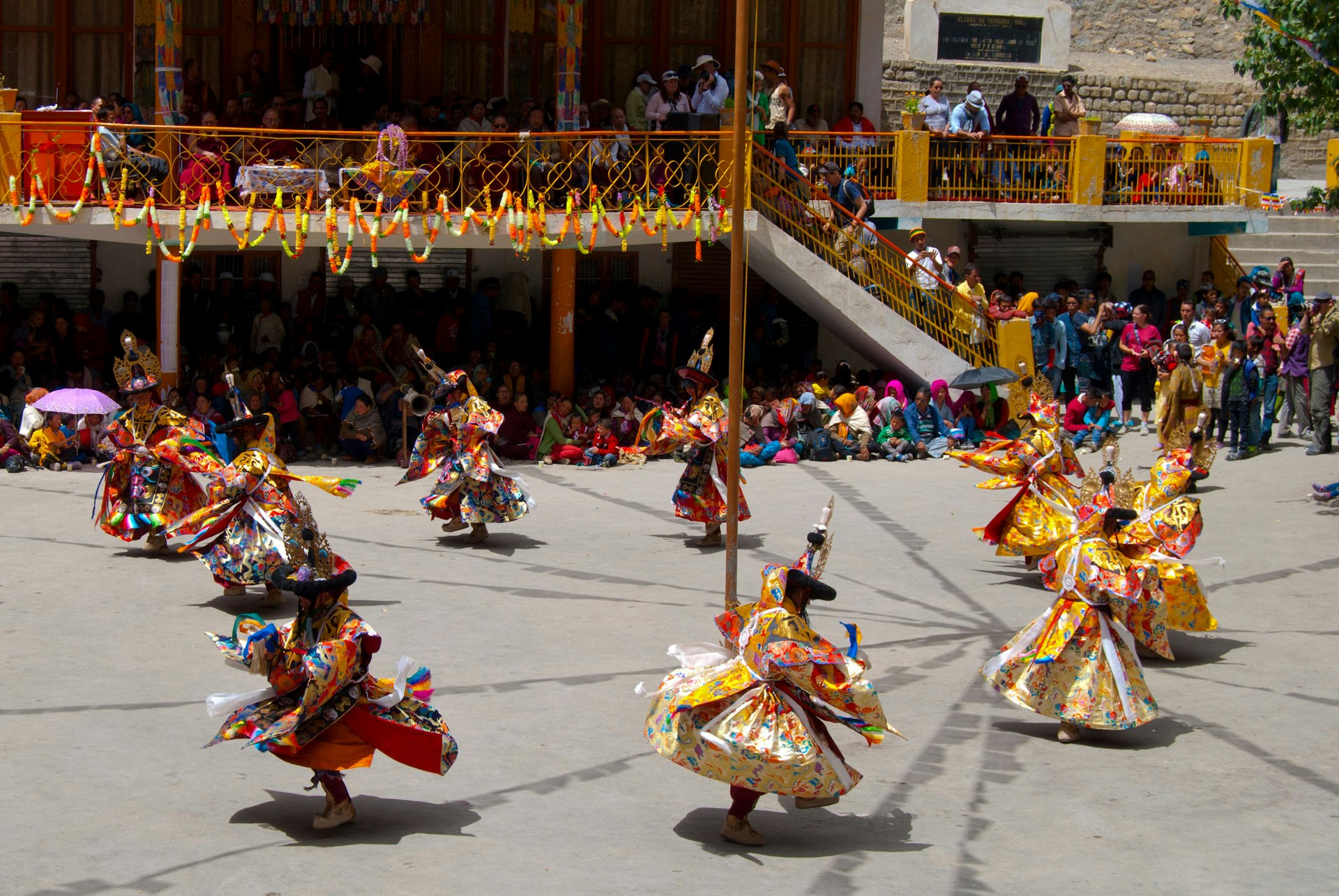 Monks in colourful costumes dance in the courtyard at Ki Gompa