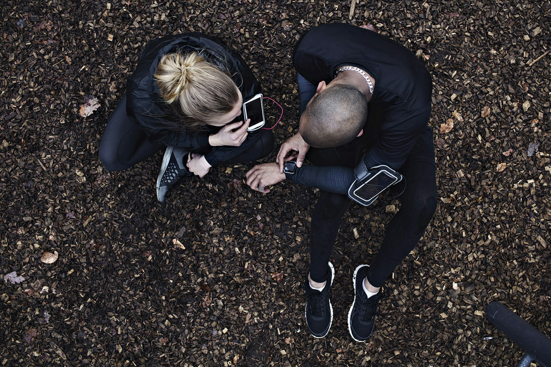 Features - Directly above shot of couple using technologies while exercising in forest
