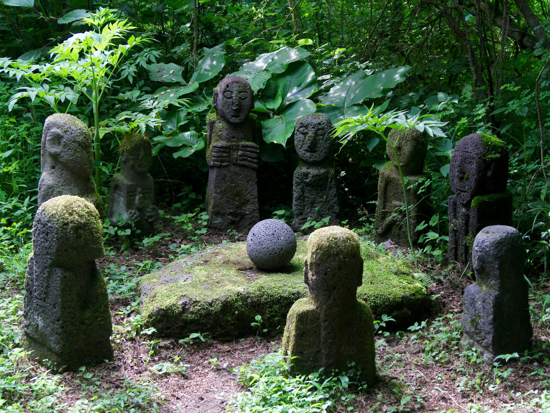 Statues of local spirits in forest glade at Jeju Stone Park © Simon Richmond / Lonely Planet