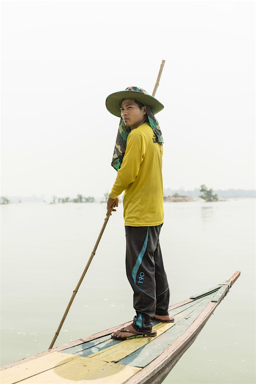 Features - 4000 Islands, Laos Mr Jong guides himself through the shallows of the Mekong on his boat