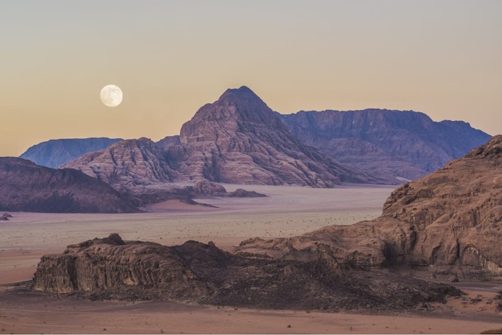 A pale red landscape stretches out, with rocks and hills. The moon can be seen in the sky, which is slightly yellow giving the scene an eerie feel