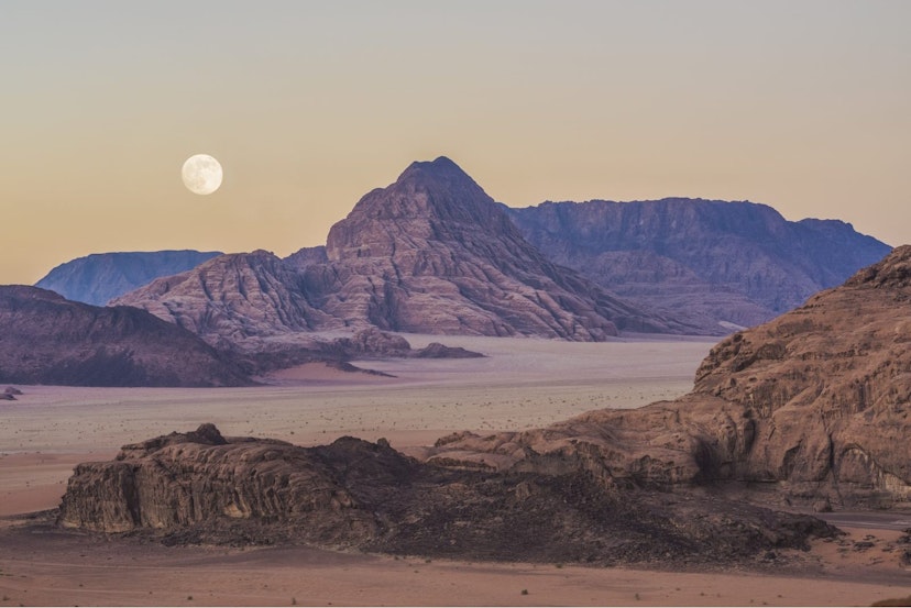 A pale red landscape stretches out, with rocks and hills. The moon can be seen in the sky, which is slightly yellow giving the scene an eerie feel