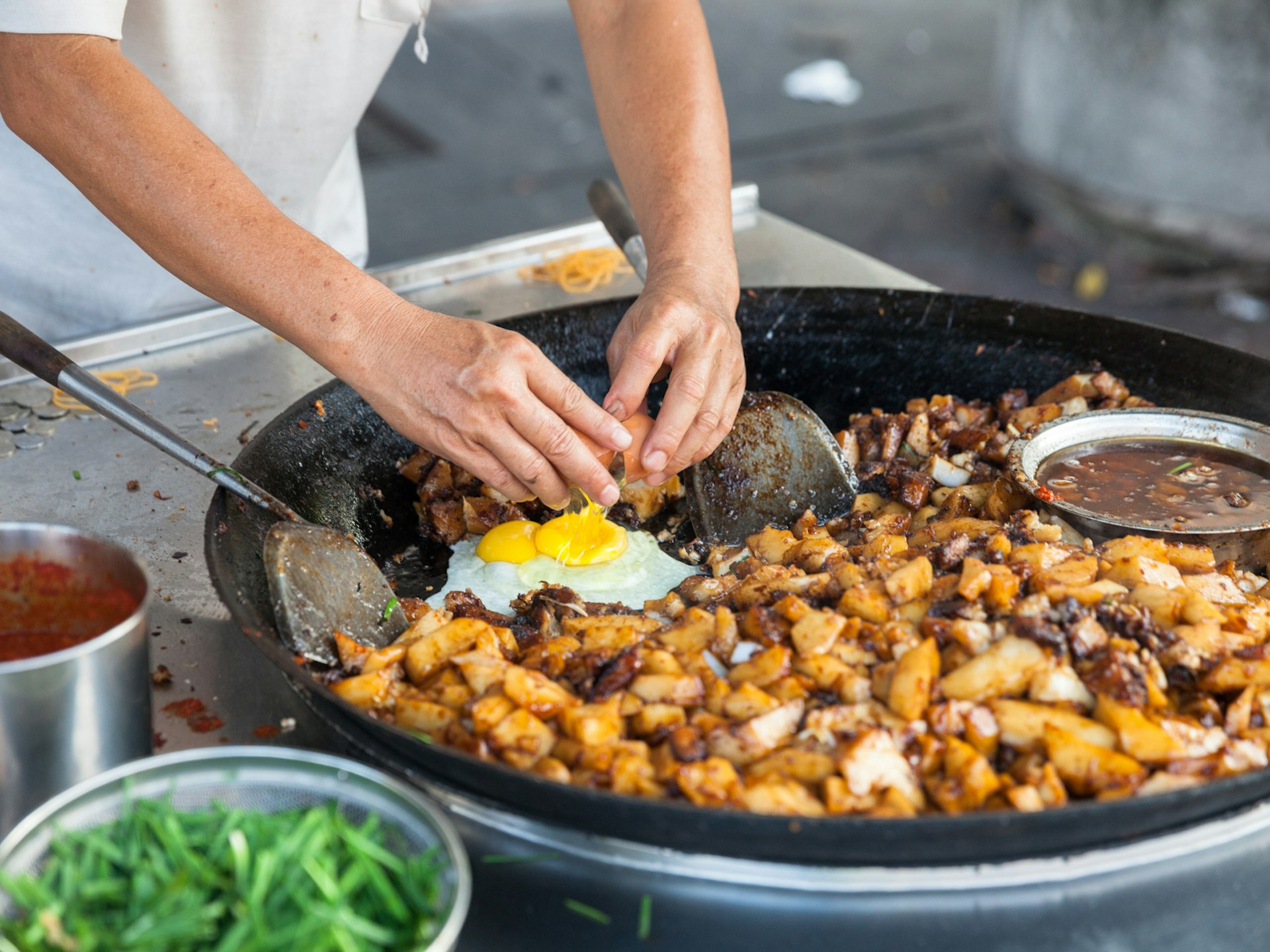 A chef cracks an egg into a pan of food at George Town's Kimberly Street Food Night Market, Penang, Malaysia