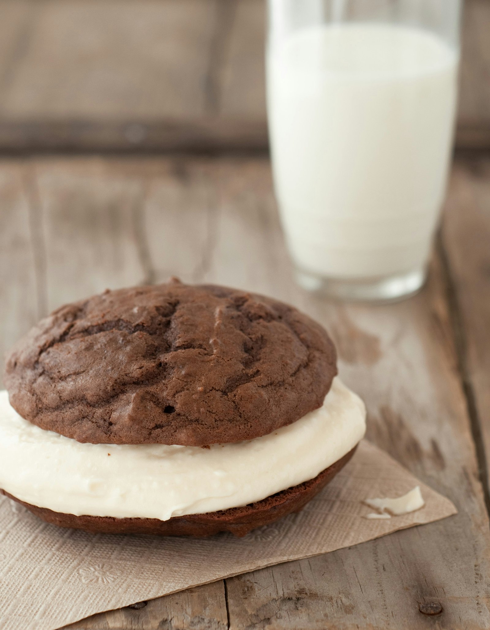 a black whoopie pie with white filling and a glass of milk