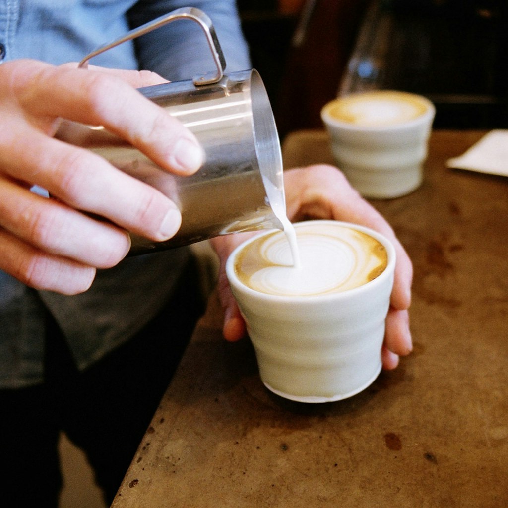 Someone pouring milk into a coffee at Barrio, Canberra © Andy Mullens / Barrio