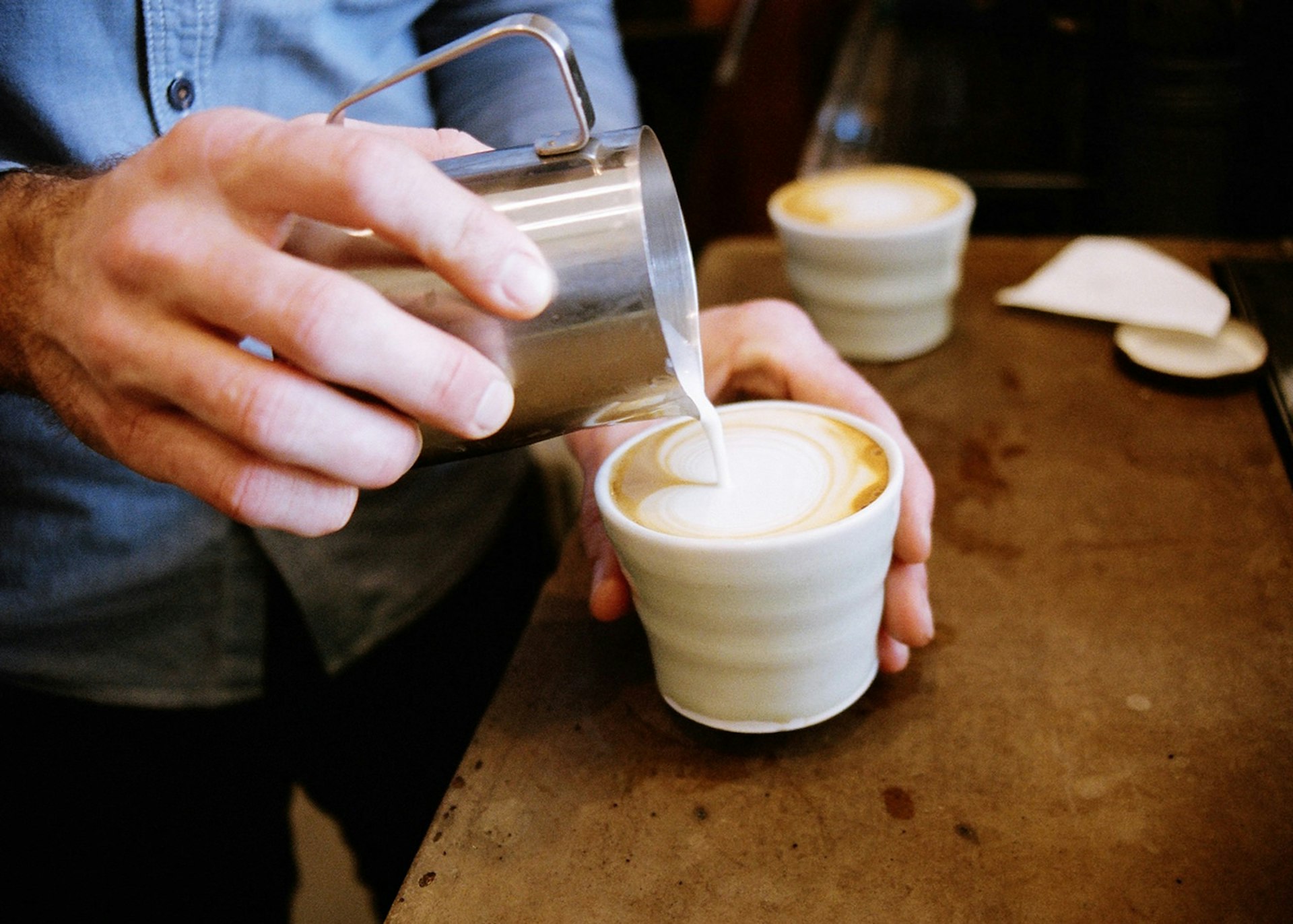 Someone pouring milk into a coffee at Barrio, Canberra © Andy Mullens / Barrio