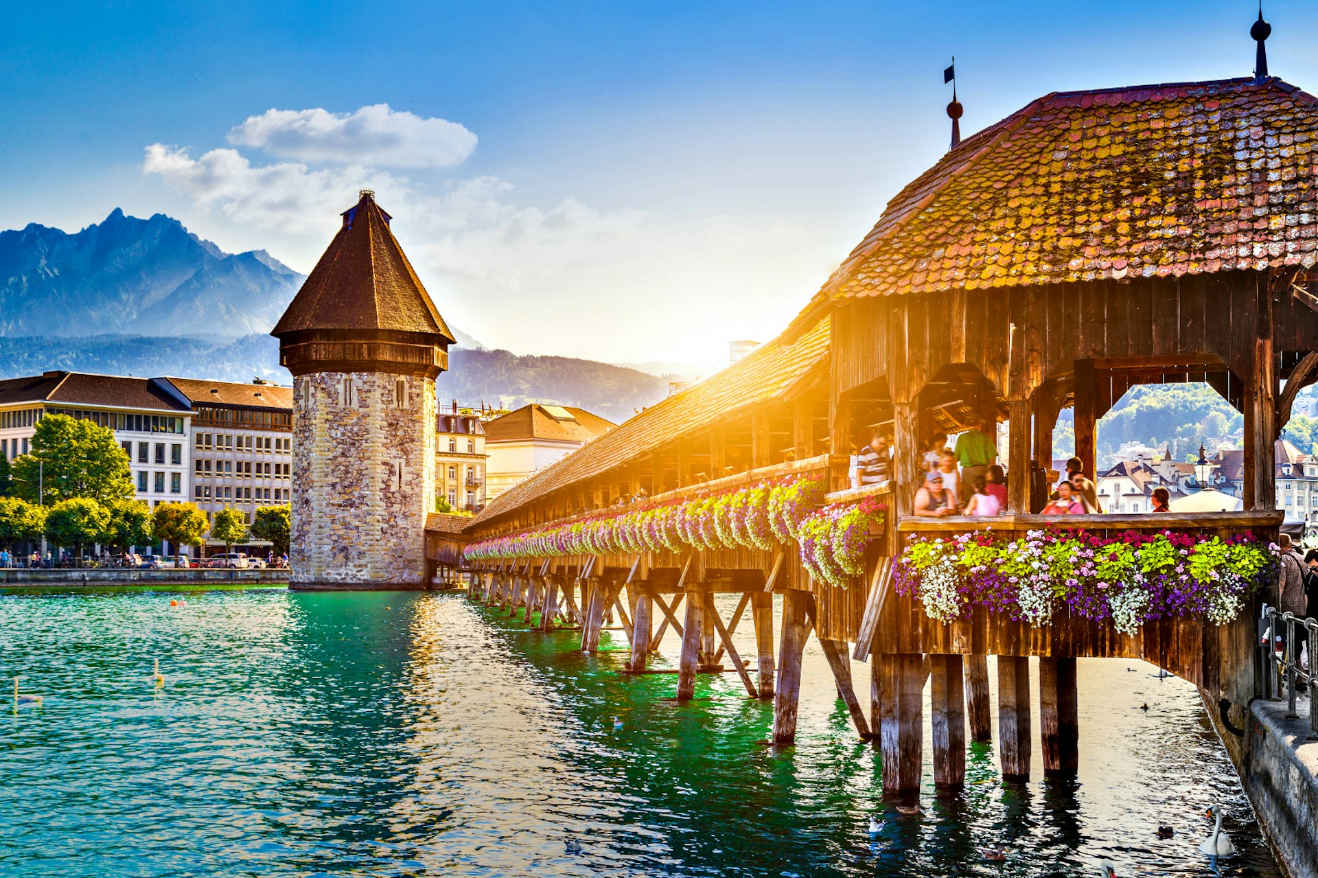 Солнце садится над мостом Капельбрюкке XIV века в Люцерне, Швейцария.