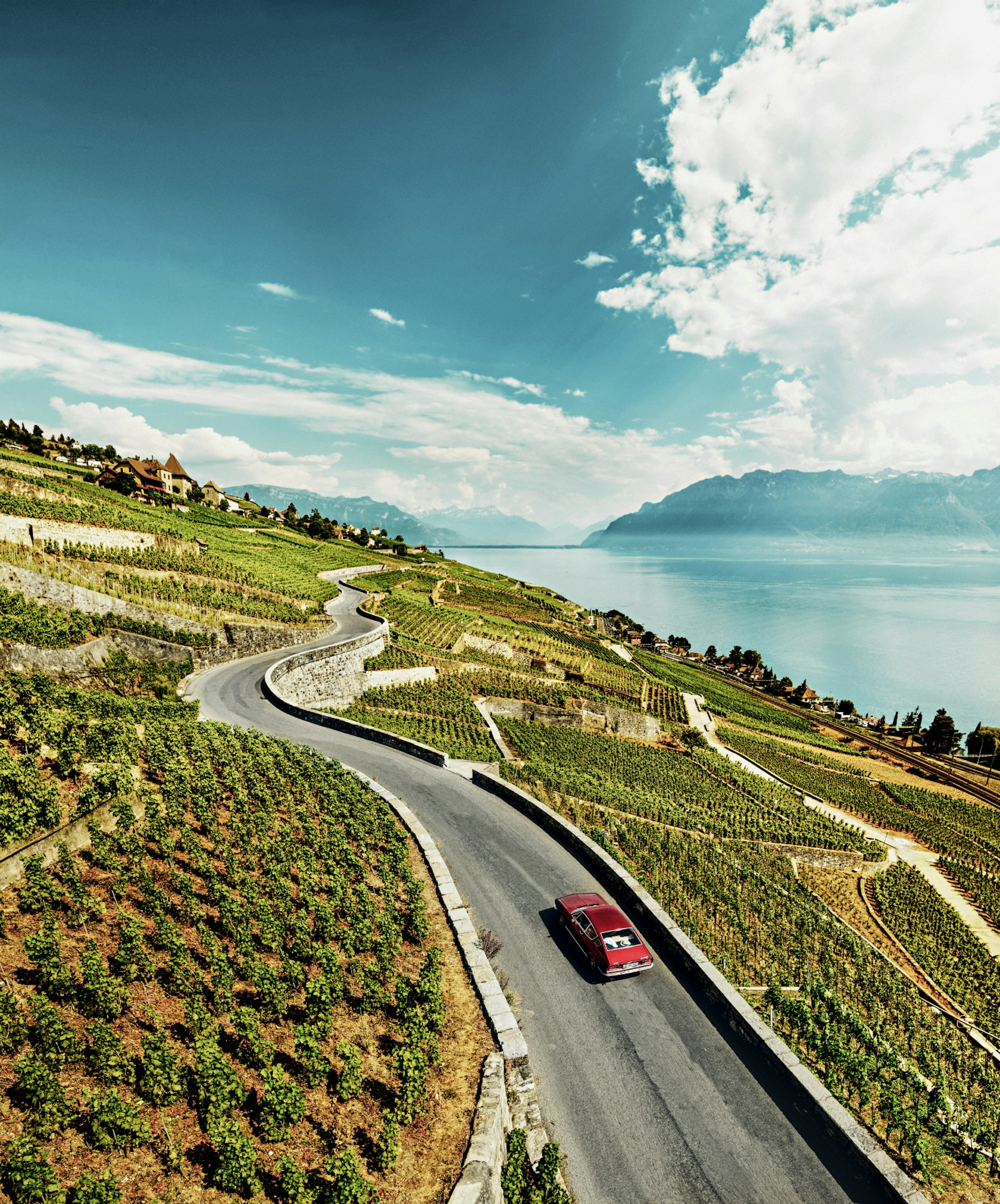 A car driving through a vineyard in Switzerland with views across a lake