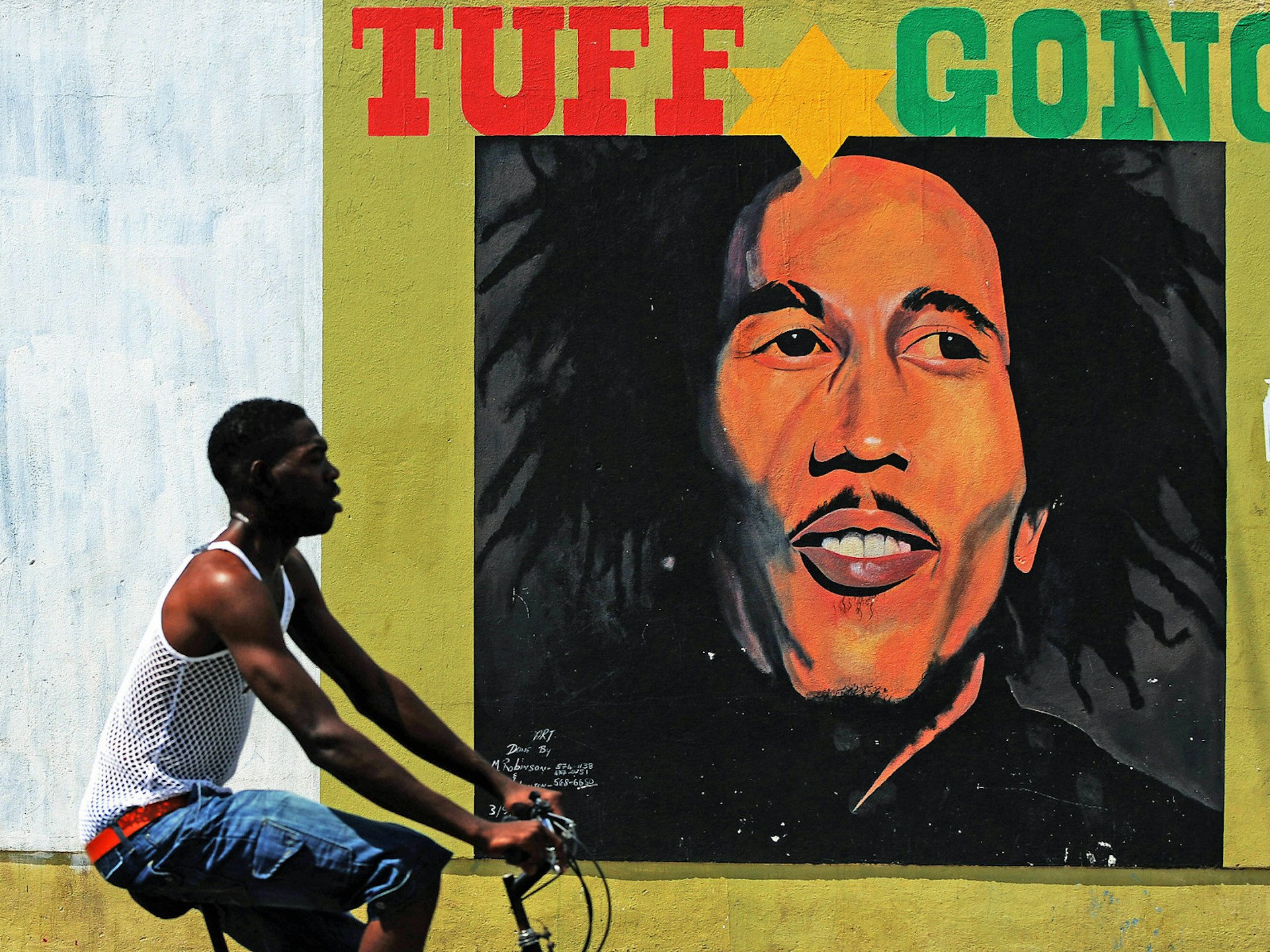 A man cycles past a large mural of Bob Marley on the streets on Kingston, Jamaica