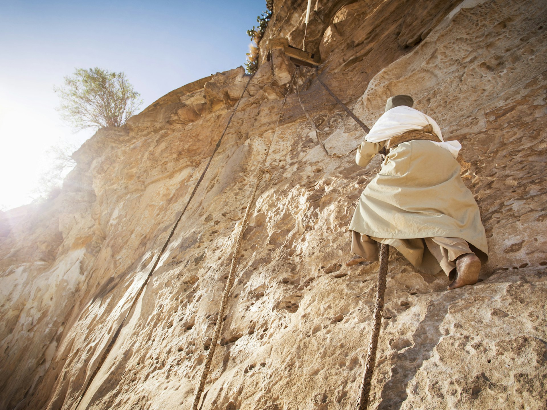 A monk scales the sheer rock face to reach Debre Damo's mountaintop monastery