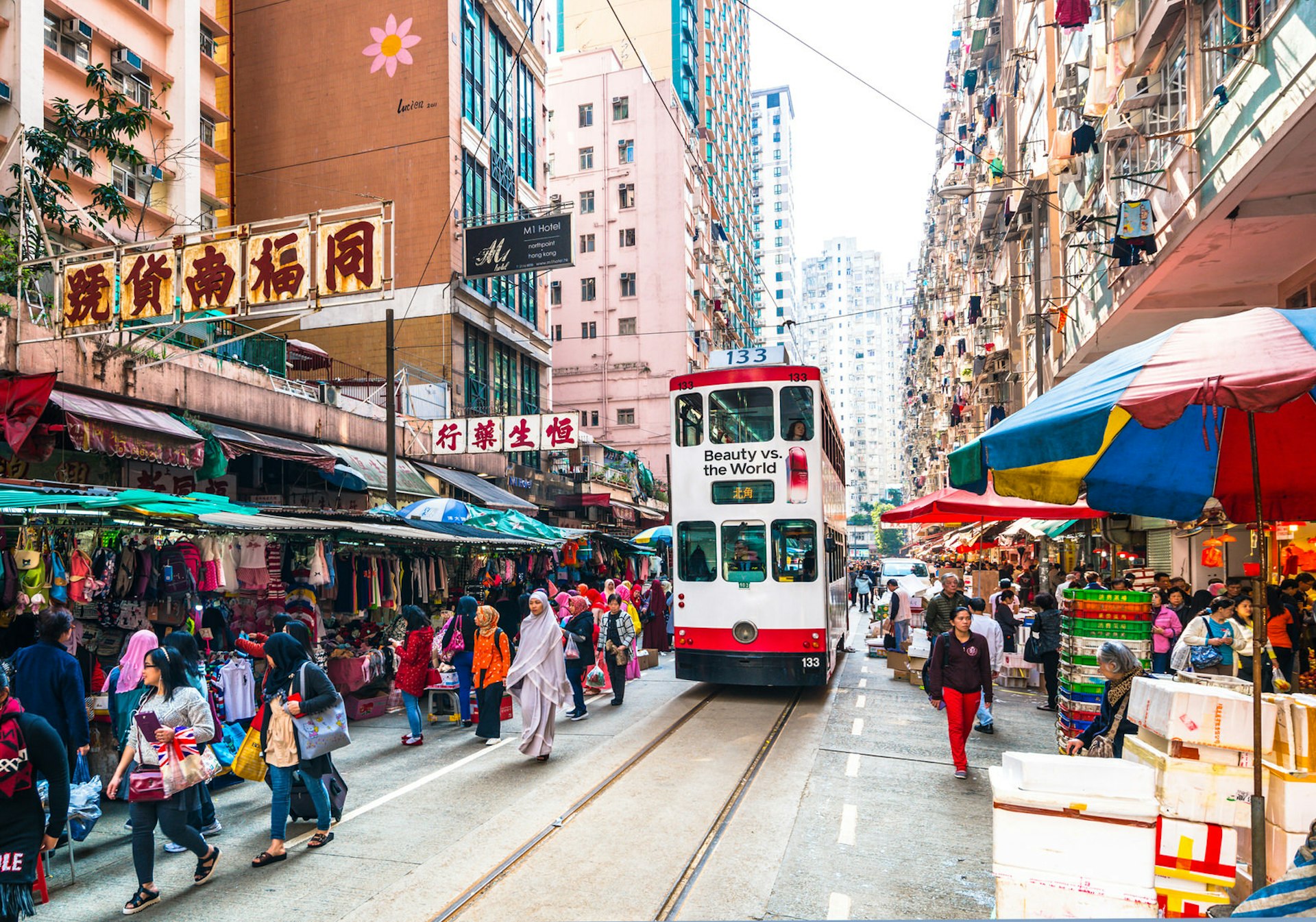 A double-decker tram moves through a market in Hong Kong