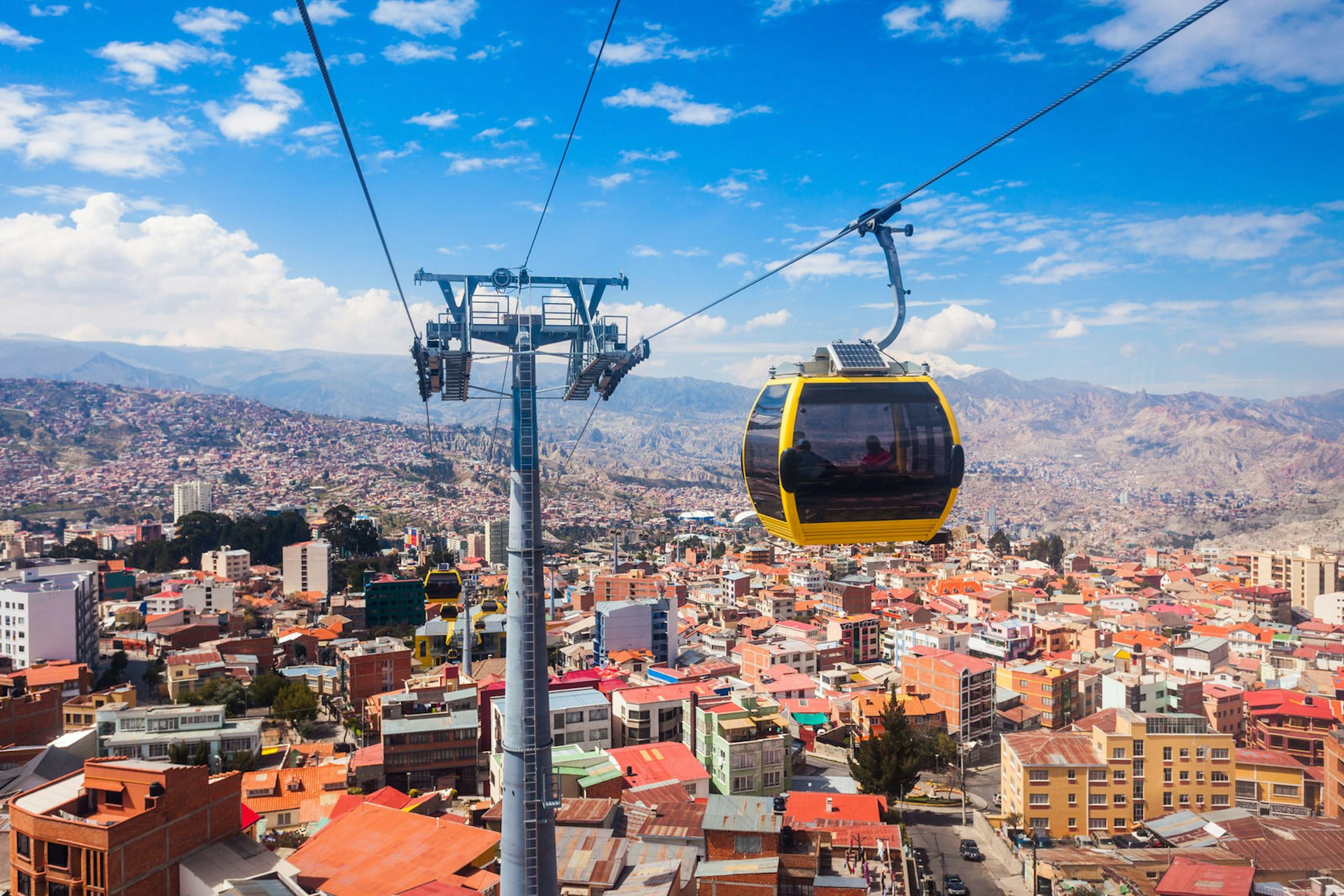 A yellow cable car hangs above the city of La Paz, Bolivia