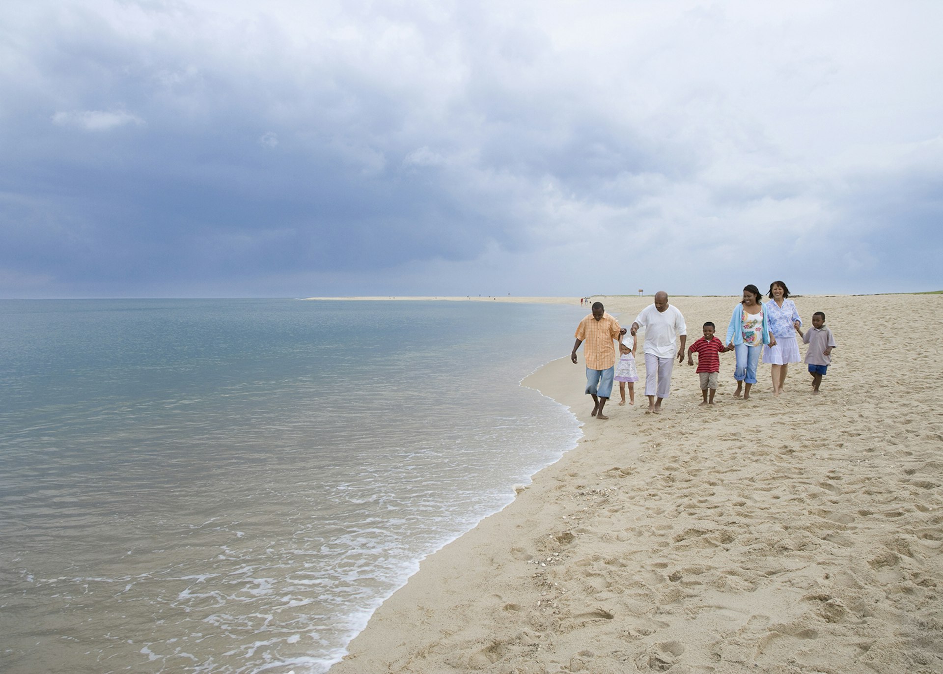 A three-generation family strolling along the beach © Jack Hollingsworth / Getty Images