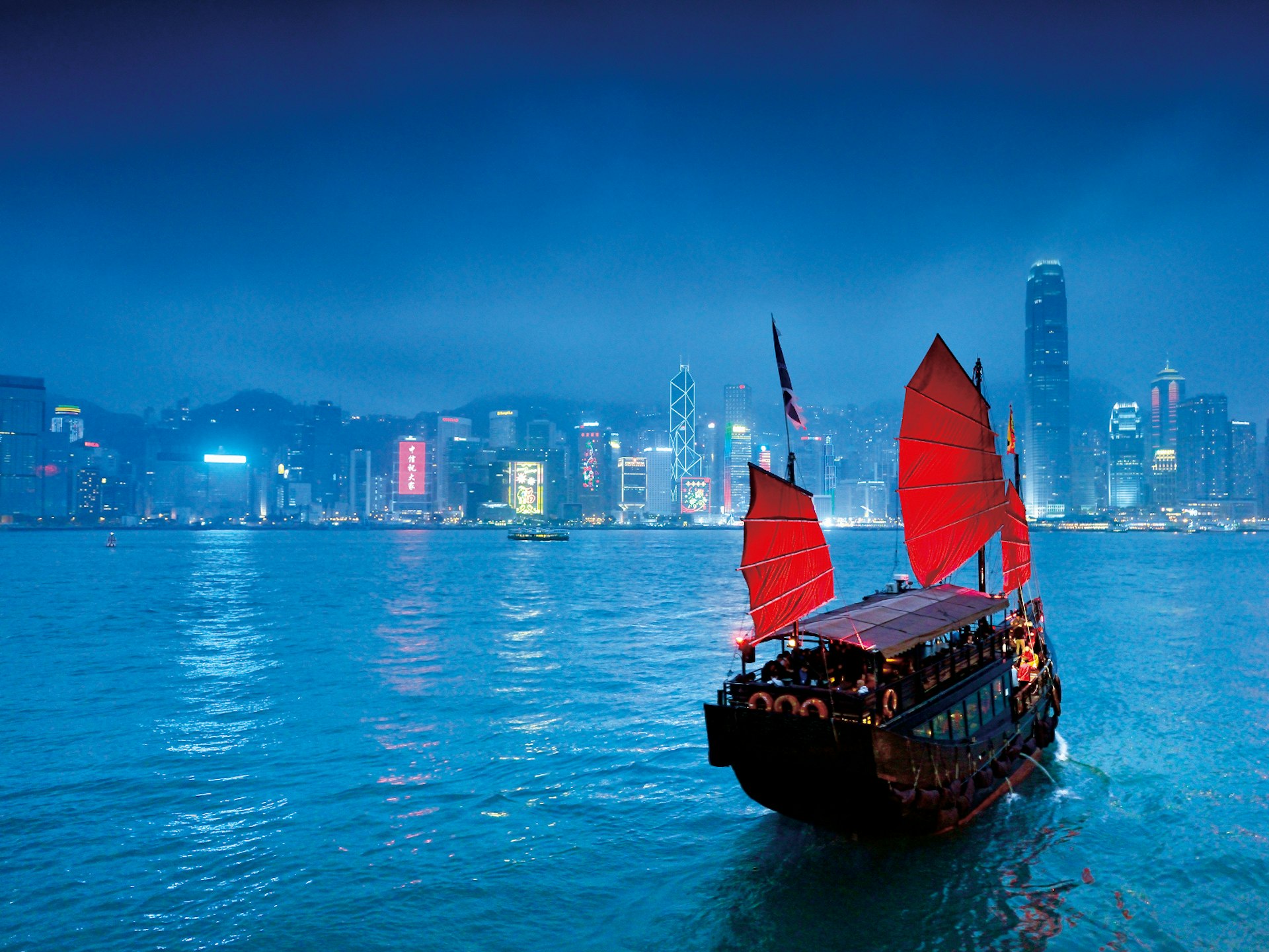 A traditional Chinese junk boat glides across the mist-shrouded Hong Kong harbour