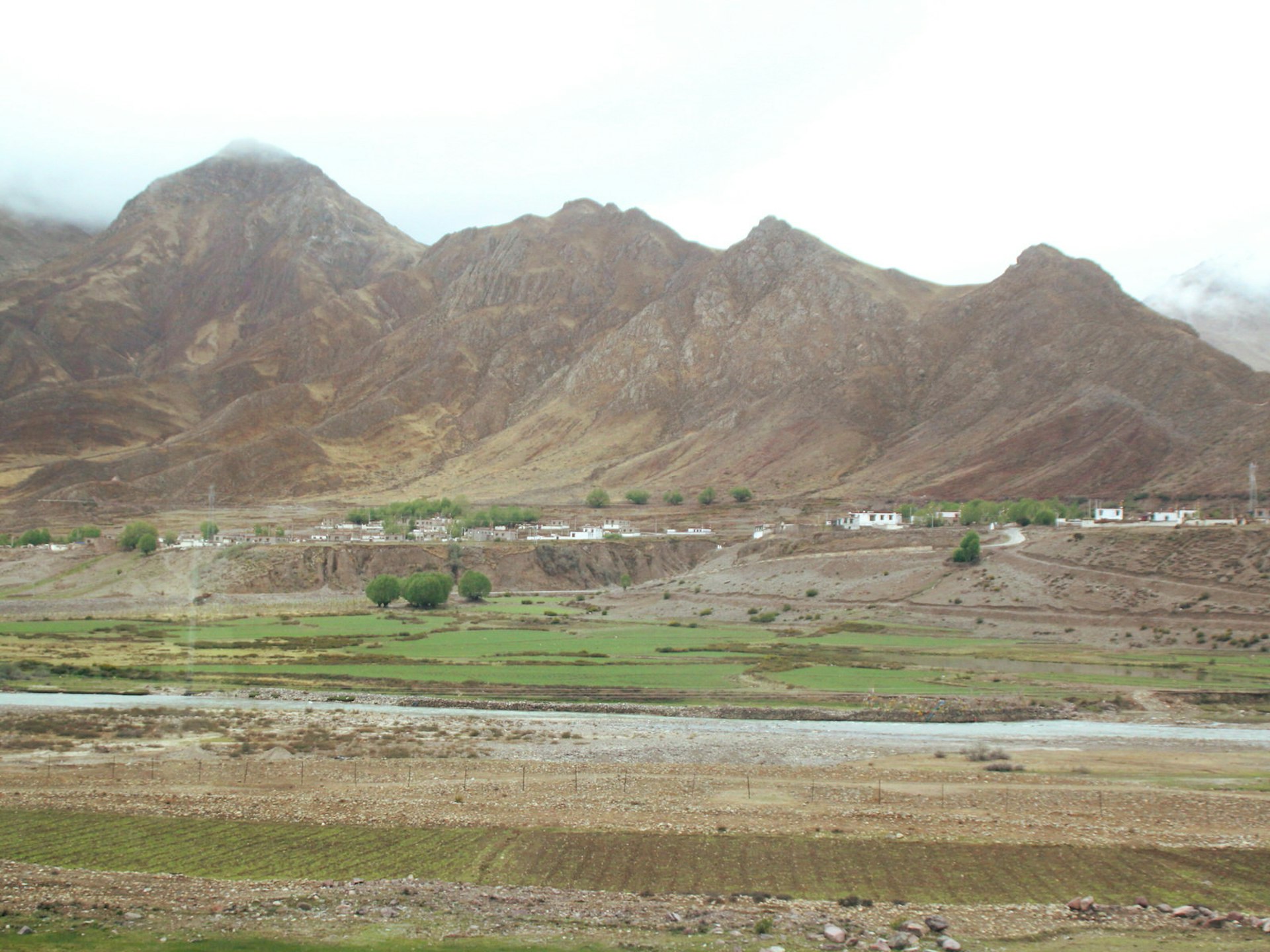 Tibetan villages and arid mountains visible from train windows © Nellie Huang / Lonely Planet