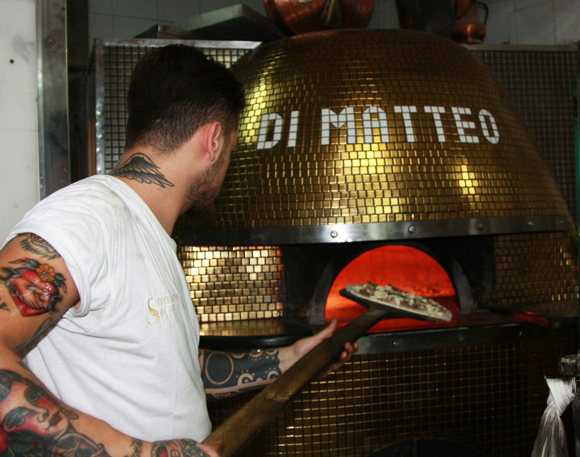 Putting the pizza in the wood-fired oven at Pizzeria Di Matteo © Kristin Melia / Lonely Planet