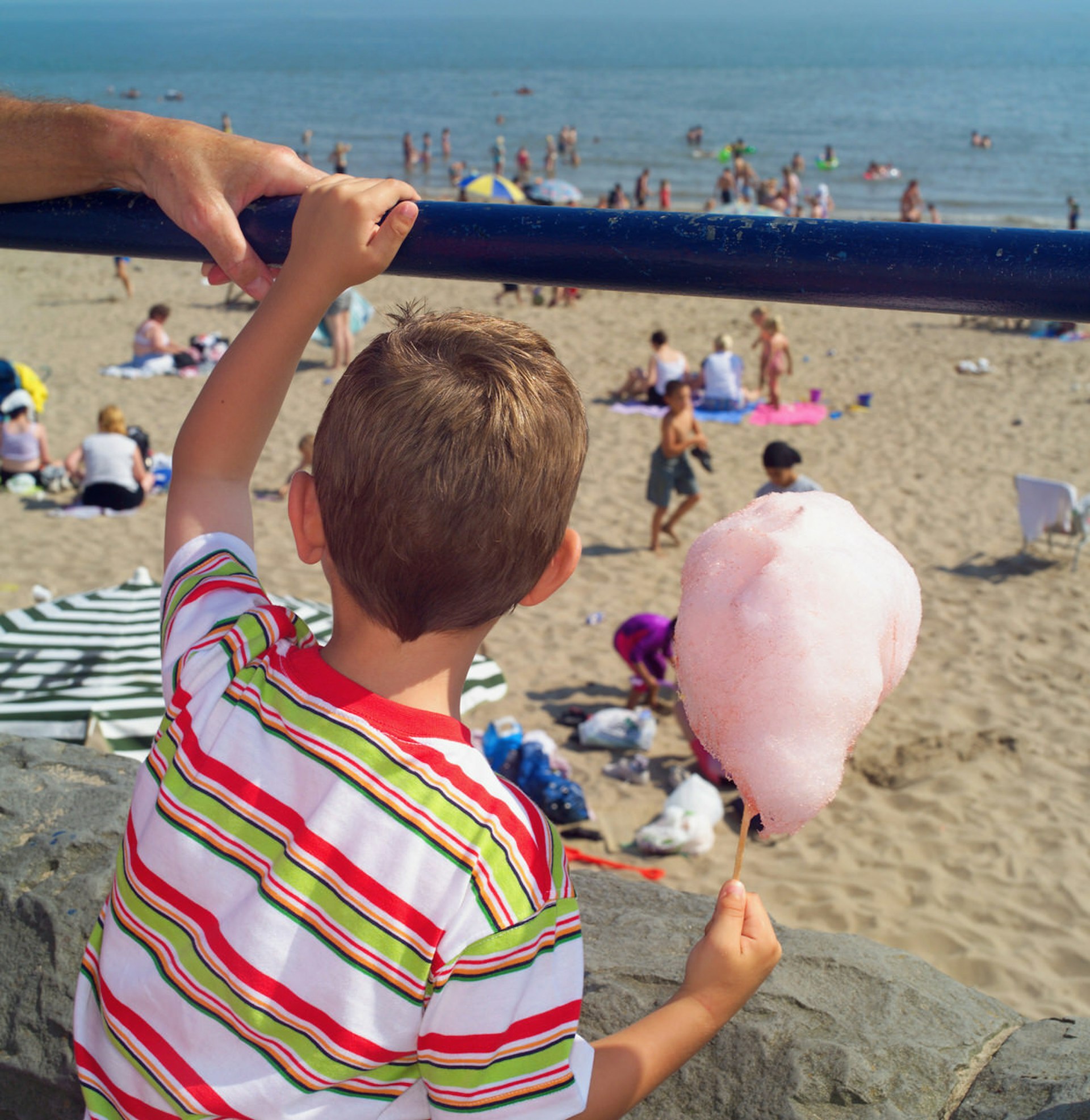 Classic seaside action on Wales' Barry Island, with pink candyfloss foregrounded against a mellow beach scene © Phil Boorman / Stockbyte / Getty Images