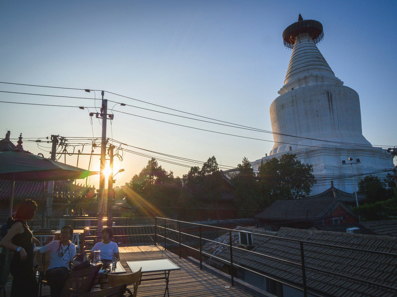 View of Miaoying Temple White Dagoba with diners and the sunset.