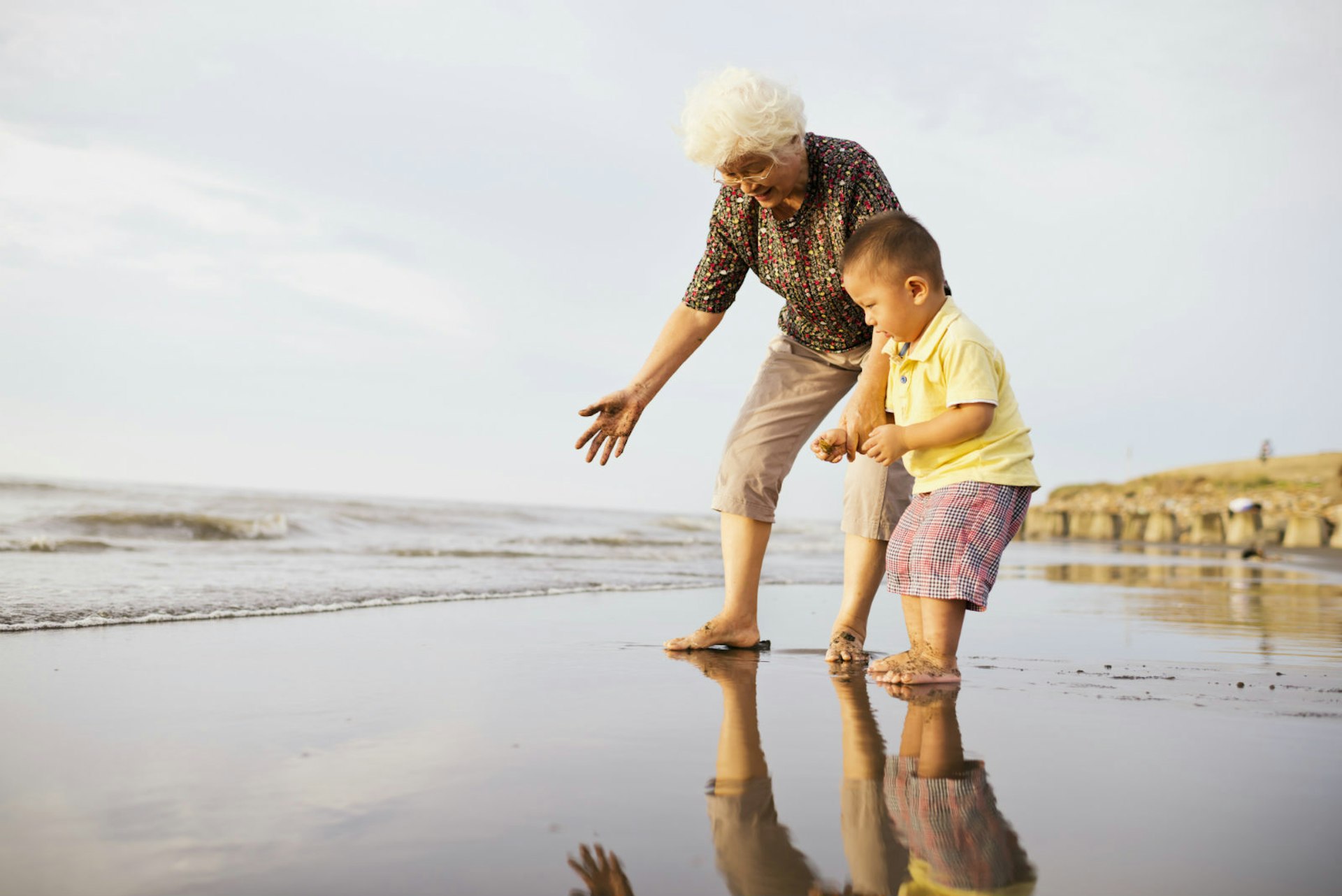 Romantic trip with kids in tow – A grandmother and grandson play on the beach.