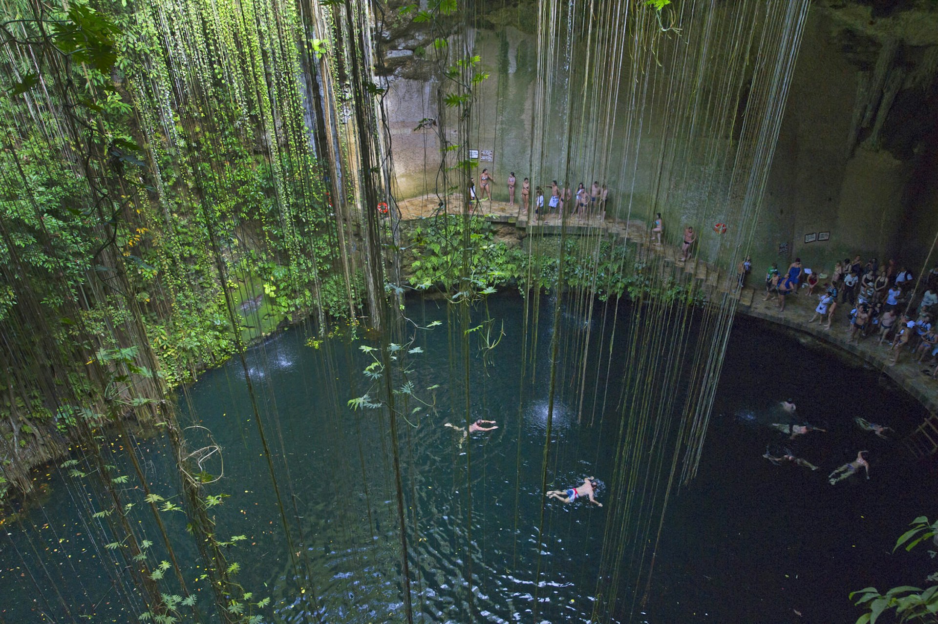 A view of a Mexican cenote from above as people queue to jump in
