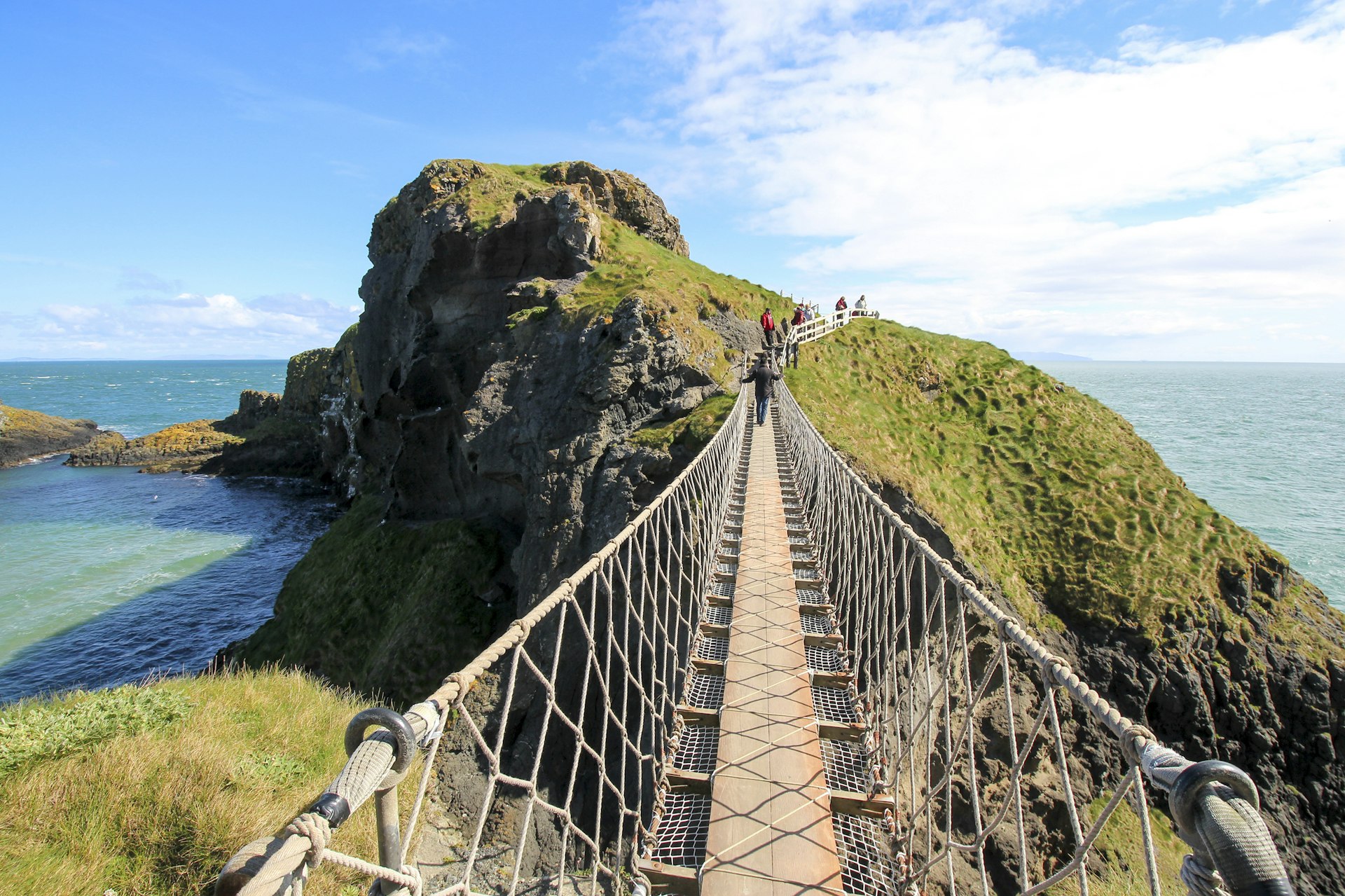 Features - Standing on Carrick-a-Rede Rope Bridge, a famous rope bridge near Ballintoy in County Antrim, Northern Ireland, UK