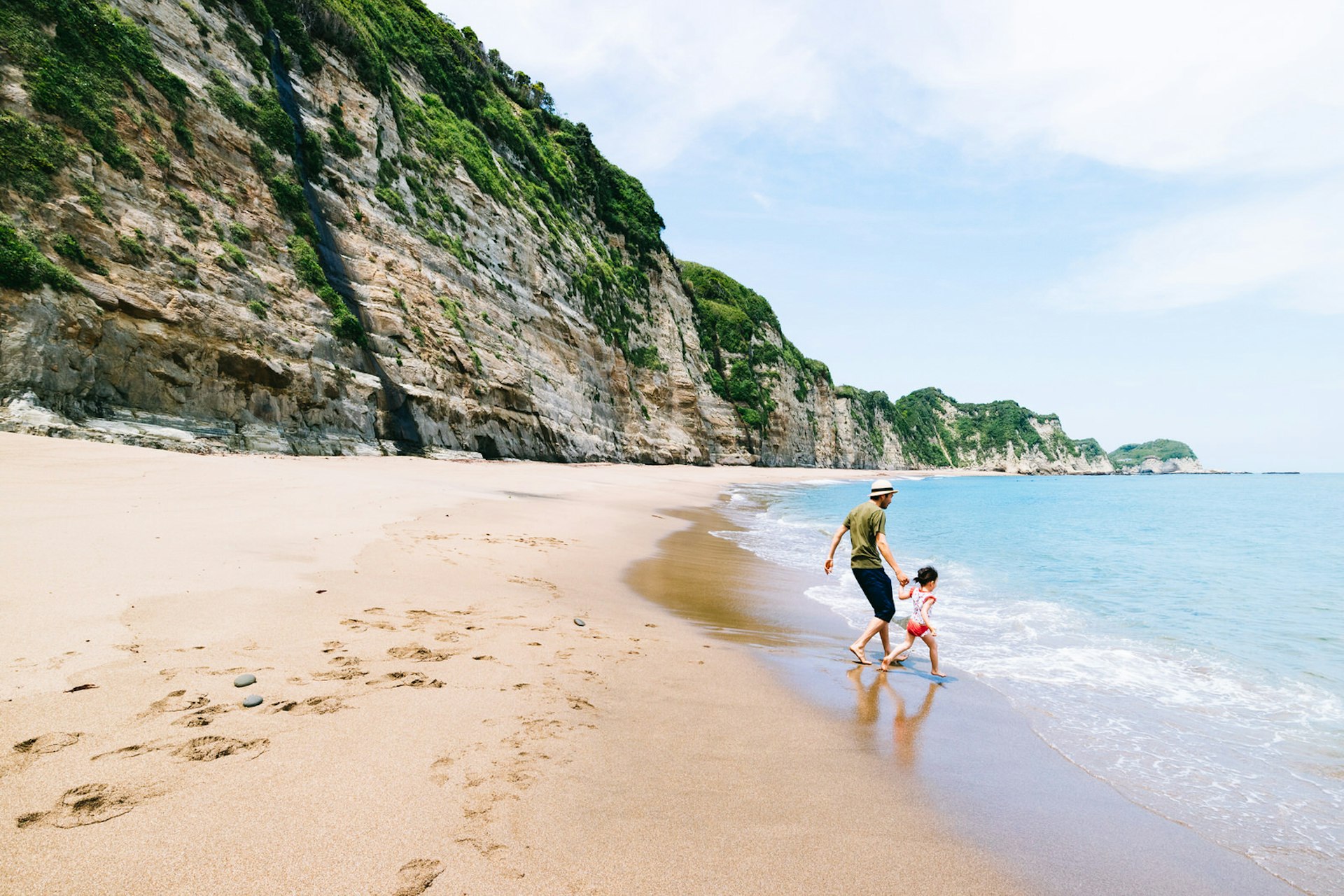 Romantic trip with kids in tow – a father and daughter walk along the coastline in Japan.