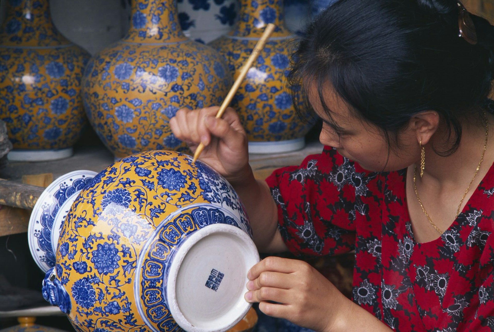 wedding anniversary trip ideas - a woman paints a porcelain vase in Jingdezhen, China.