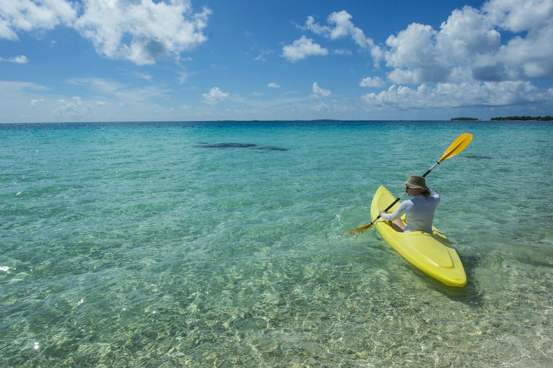 wedding anniversary trip ideas - a person kayaking in the clear waters of French Polynesia.