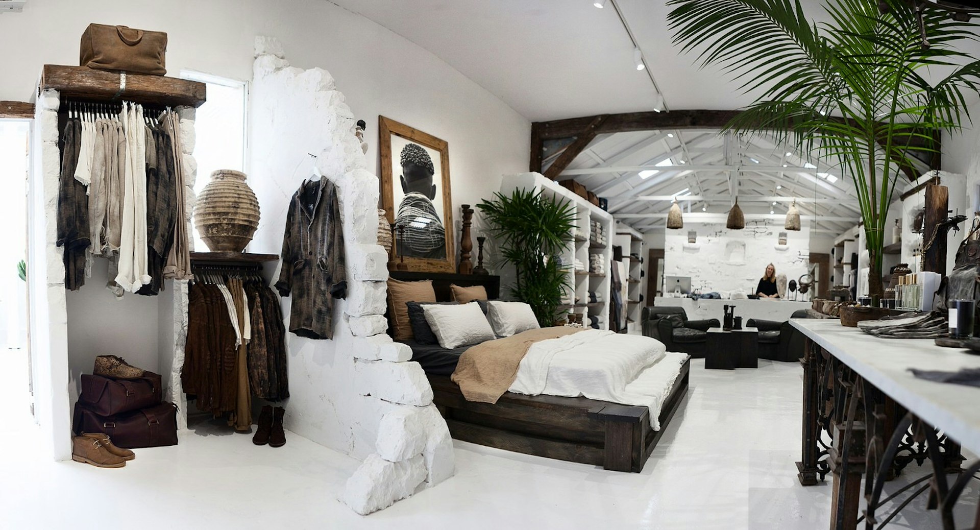 Neutral coloured, bohemian clothes hang in a white washed store also selling earthy homeware