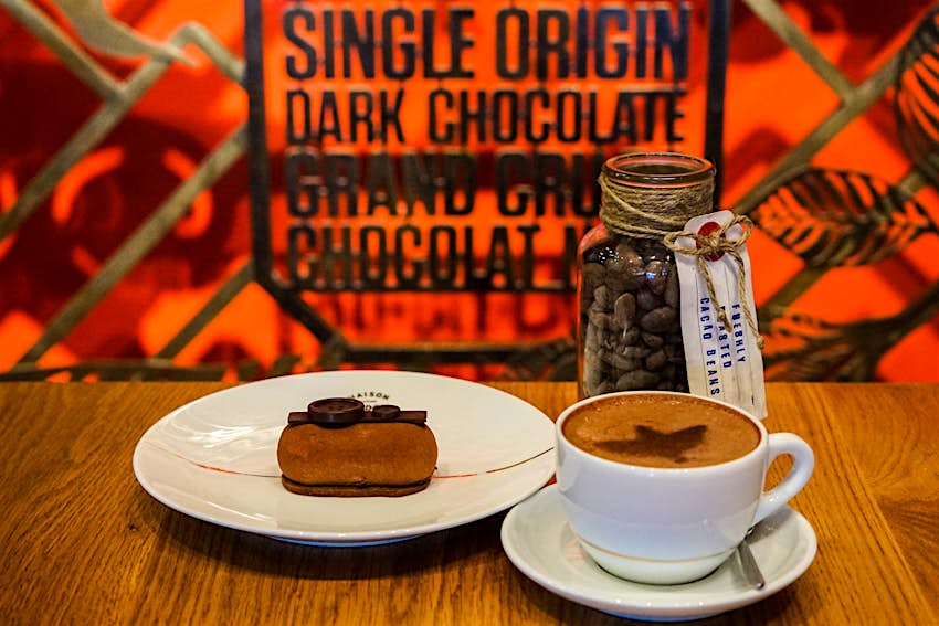One of Maison Marou's beautifully crafted chocolate desserts and a coffee in front of a dramatic red background