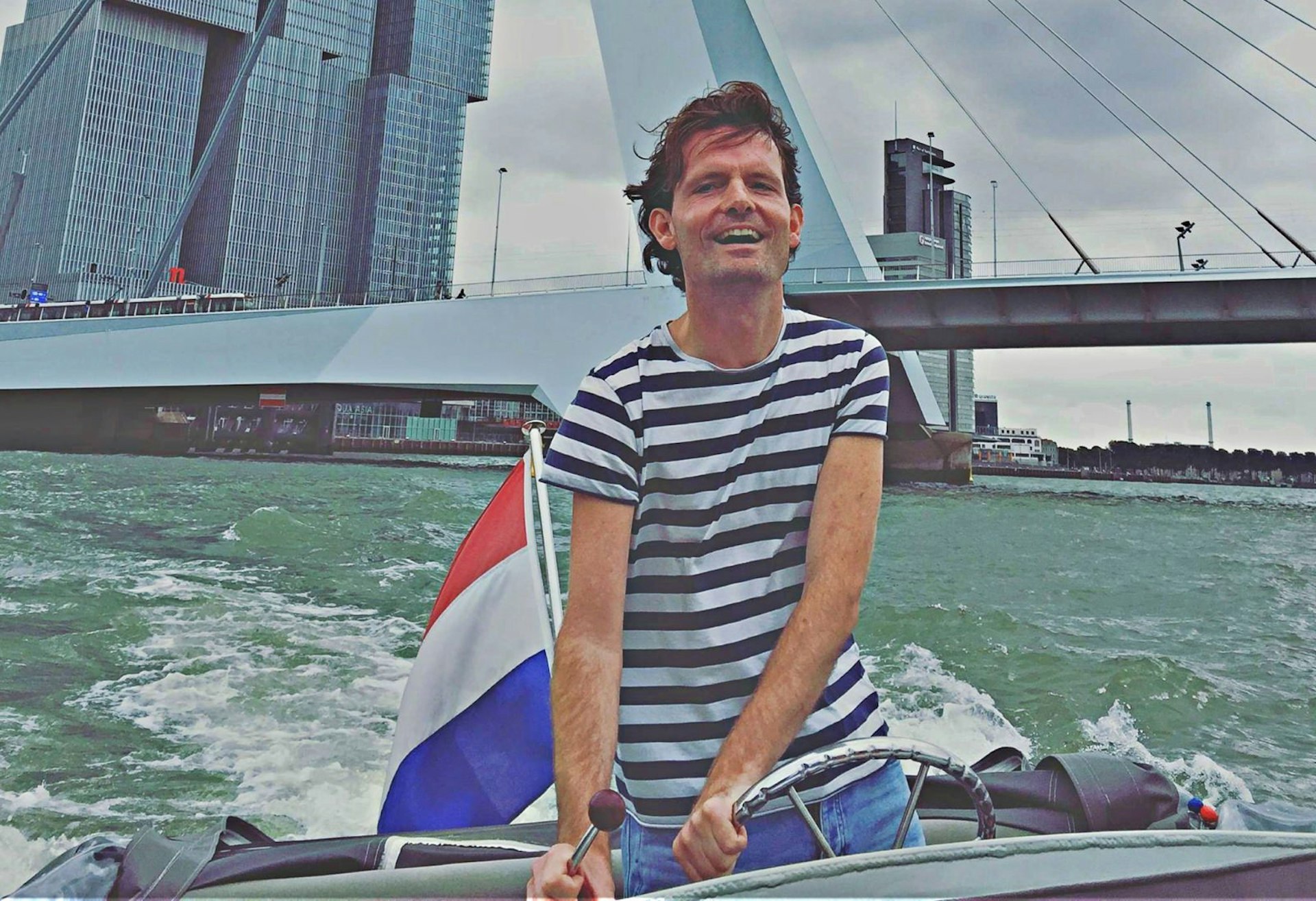 Lonely Planet Local Paul Fitzpatrick driving a boat beneath a bridge in Rotterdam