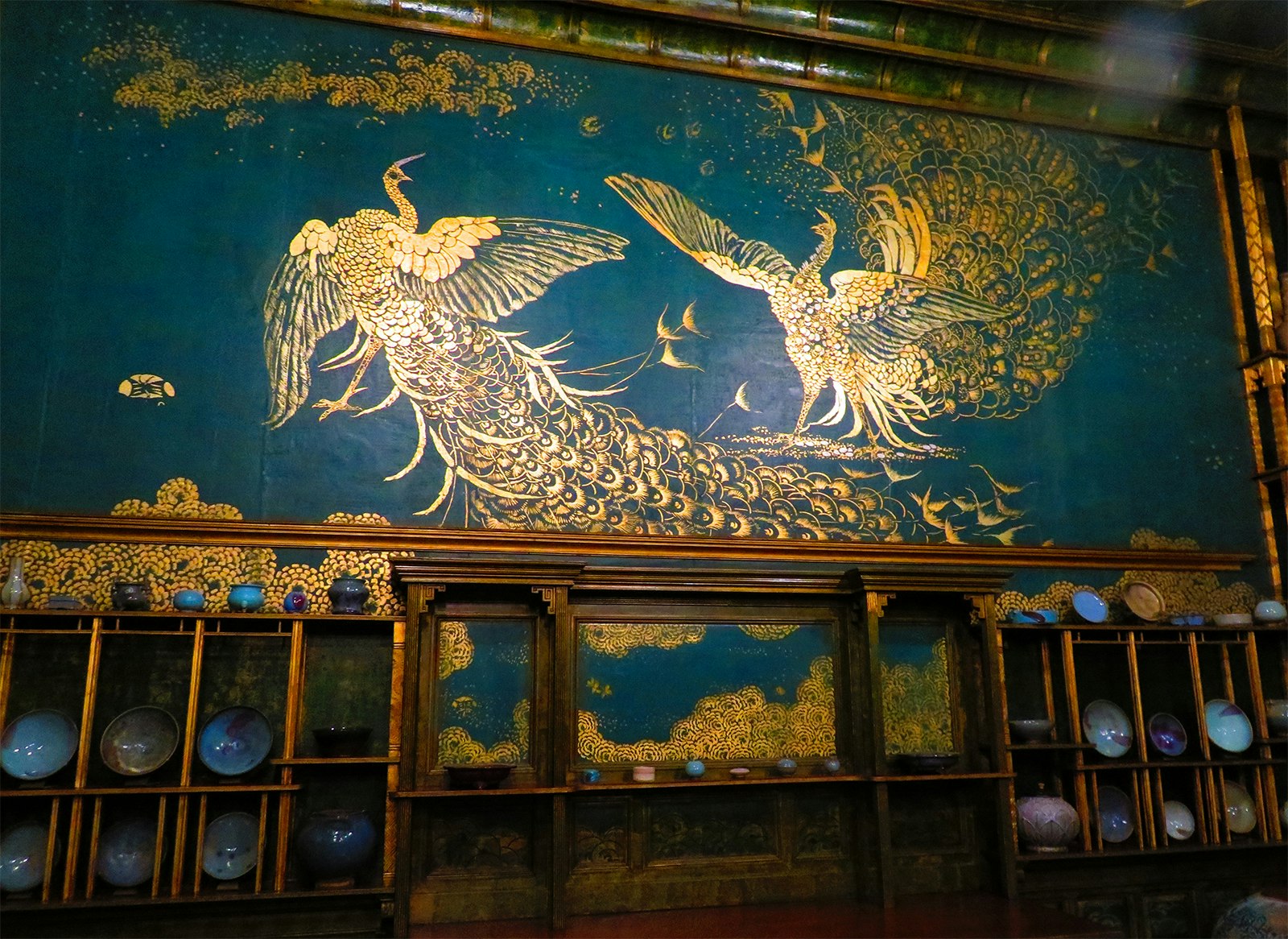 Painted peacocks fight in an ornate mural that is part of the Peacock Room