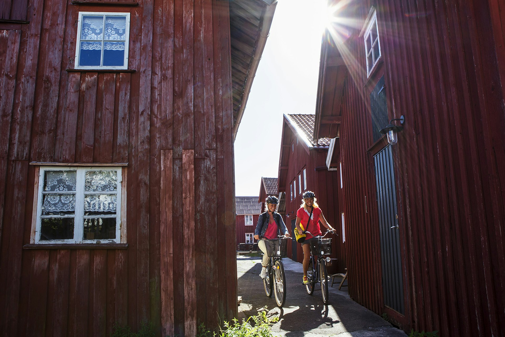 Features - Kvinnor cyklar mellan röda sjöbodar