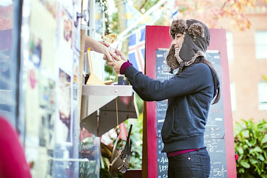 A young woman orders food from a food cart pod in Portland, Oregon.