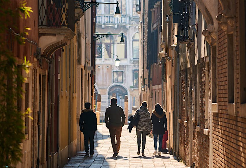 A group of people walk through a narrow alleyway in Venice