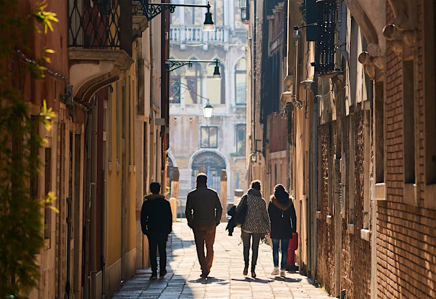 Features - Walking people in Venice A group of people walk through a narrow alleyway in Venice