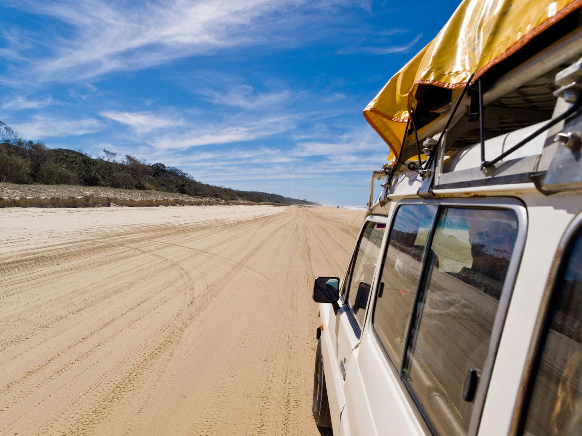 Car driving along a sandy beach on Fraser Island, Queensland, Australia
