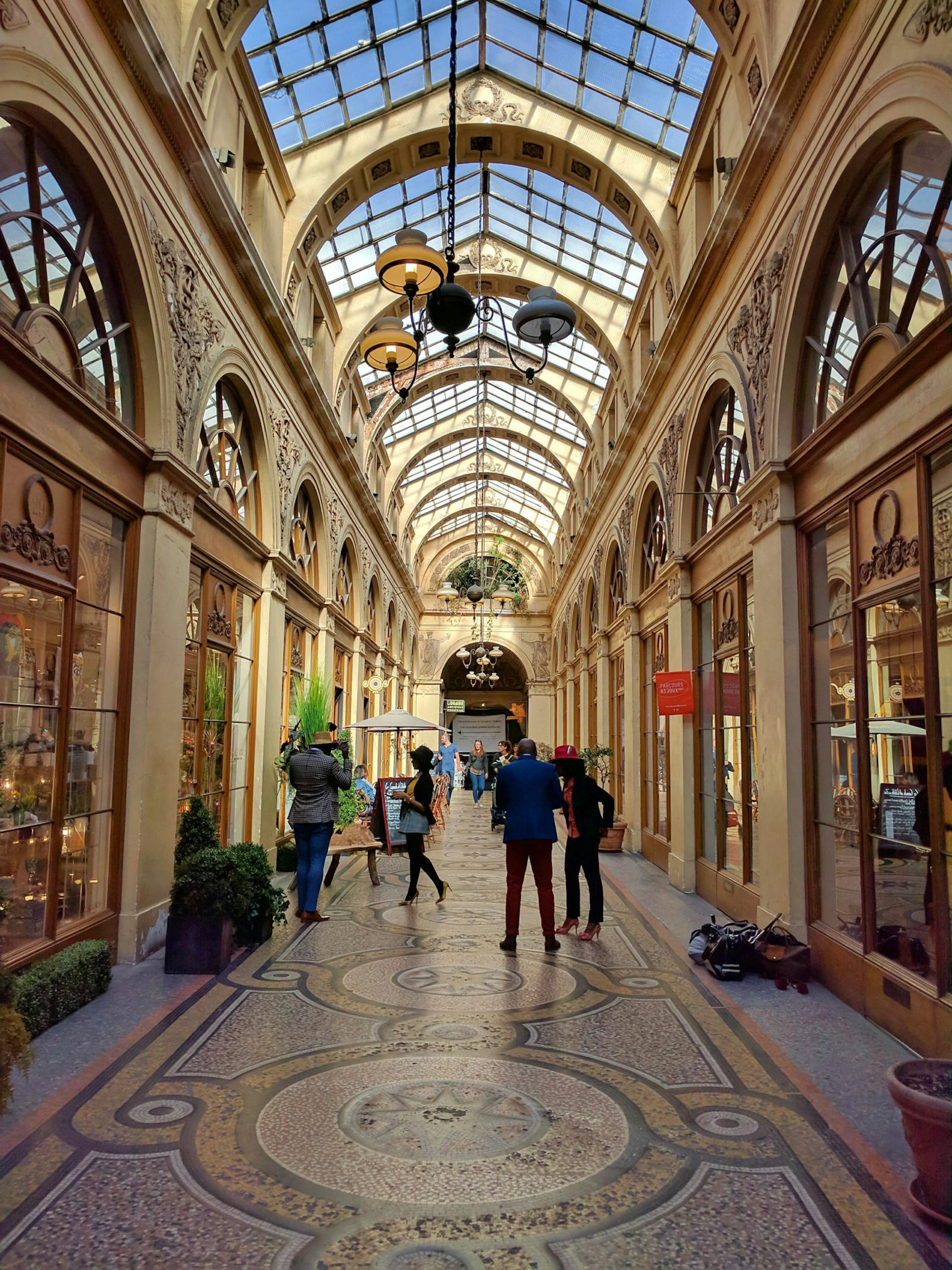 Sun sines through the glass roof of the Galerie Vivienne in Paris onto shoppers