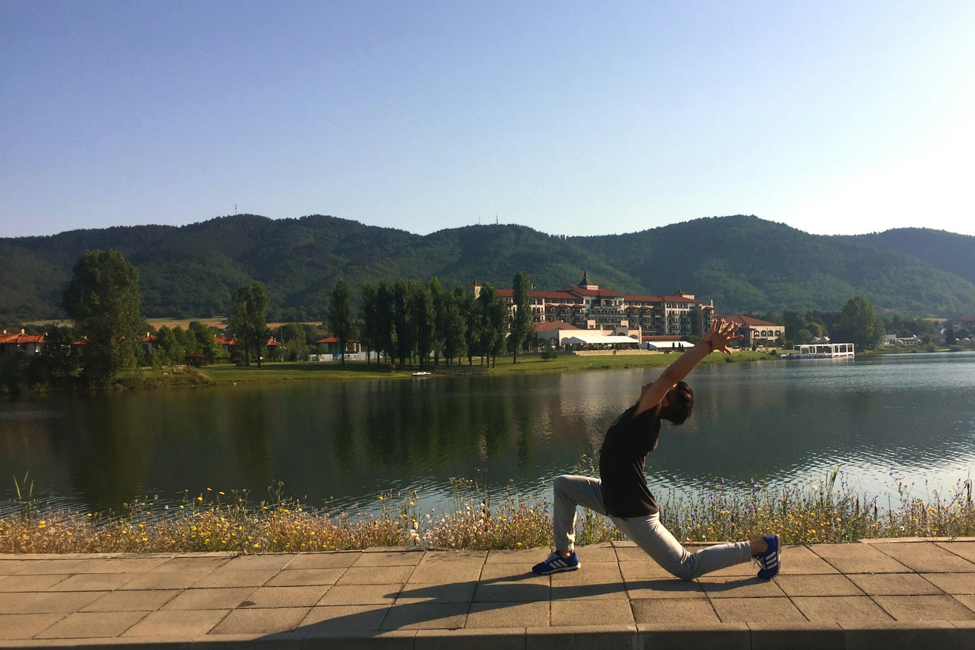 Michael James Wong does a yoga pose in front of a lake in Bulgaria