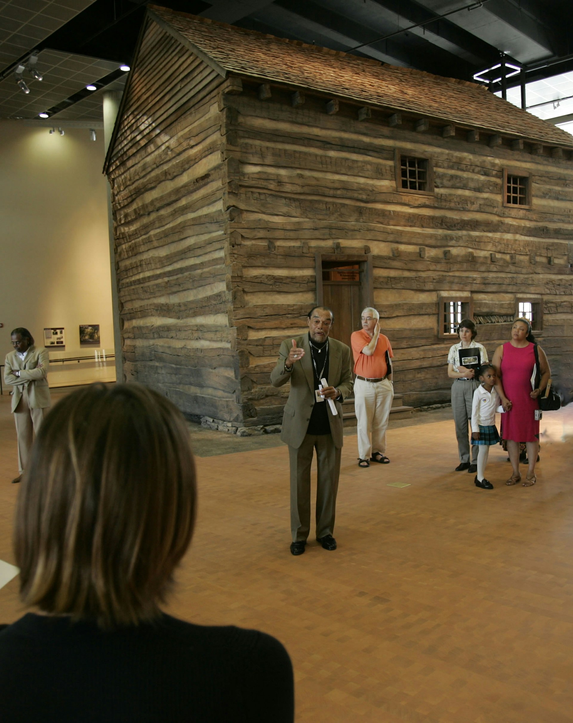 a man stands in front of a log cabin inside the National Underground Railroad Freedom Center in Cincinnati