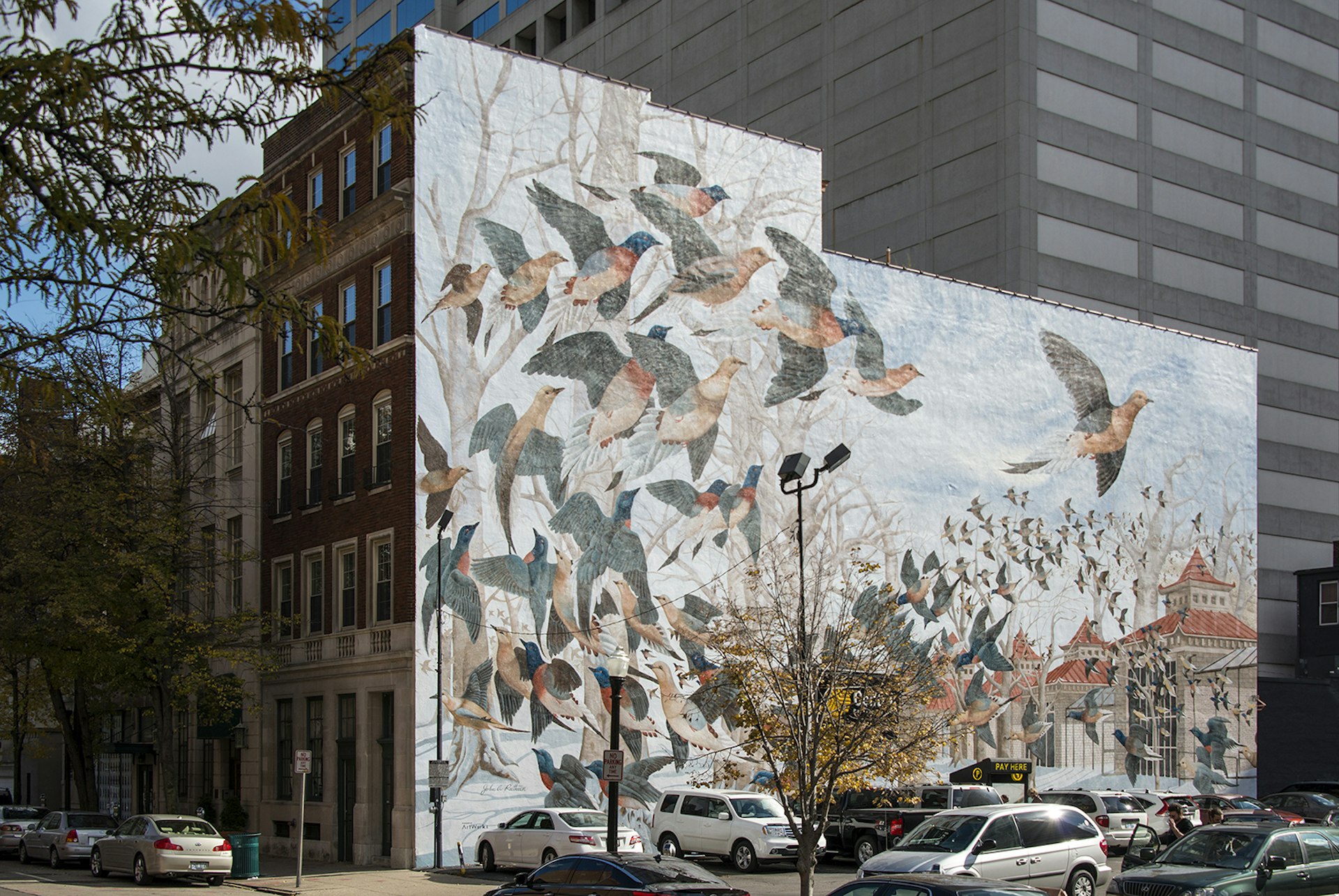 an old brick building decorated with a colorful mural of passenger pigeons