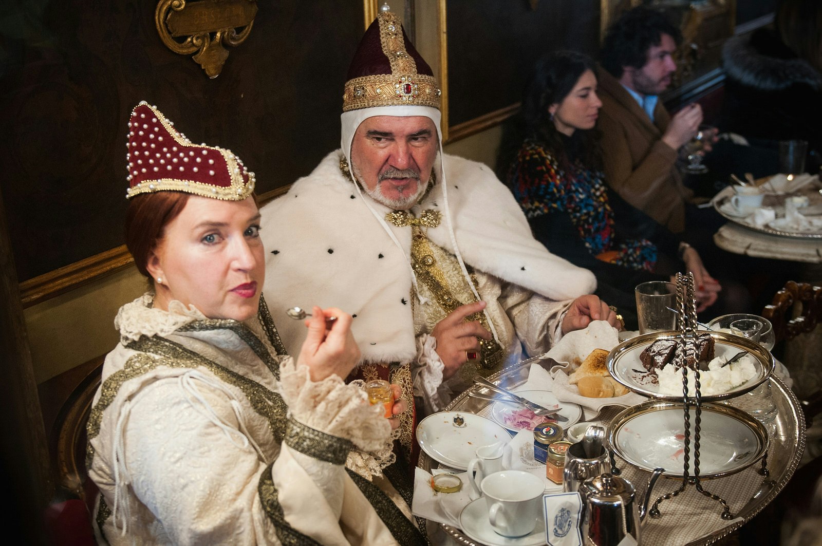 Two diners are dressed as 18th century Venetian royalty while tucking into their high tea.