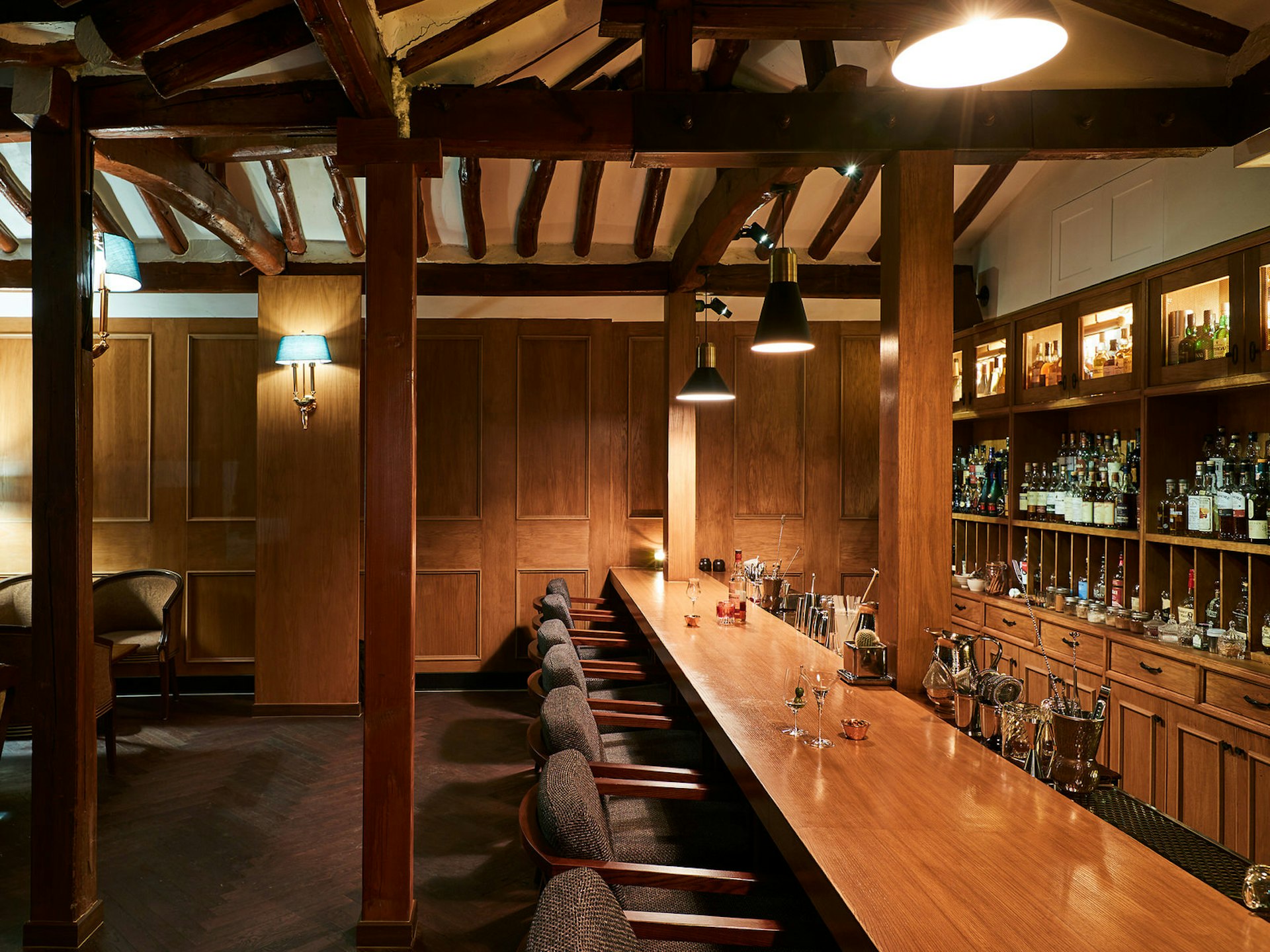 Wooden bar with seats along the bar, wooden beams and bottles of spirits