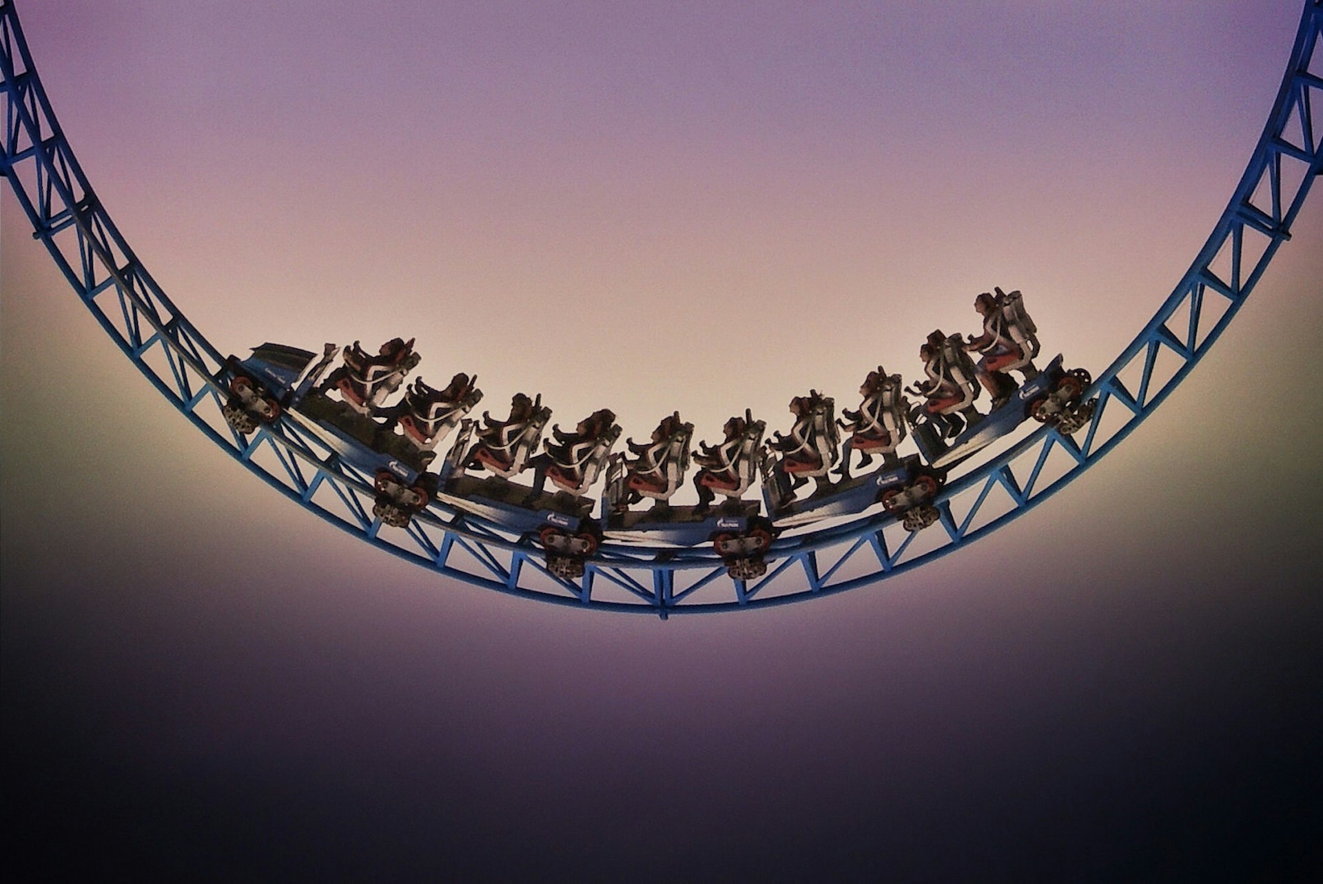 Low angle view of people on a roller coaster nearly silhouetted by the sky